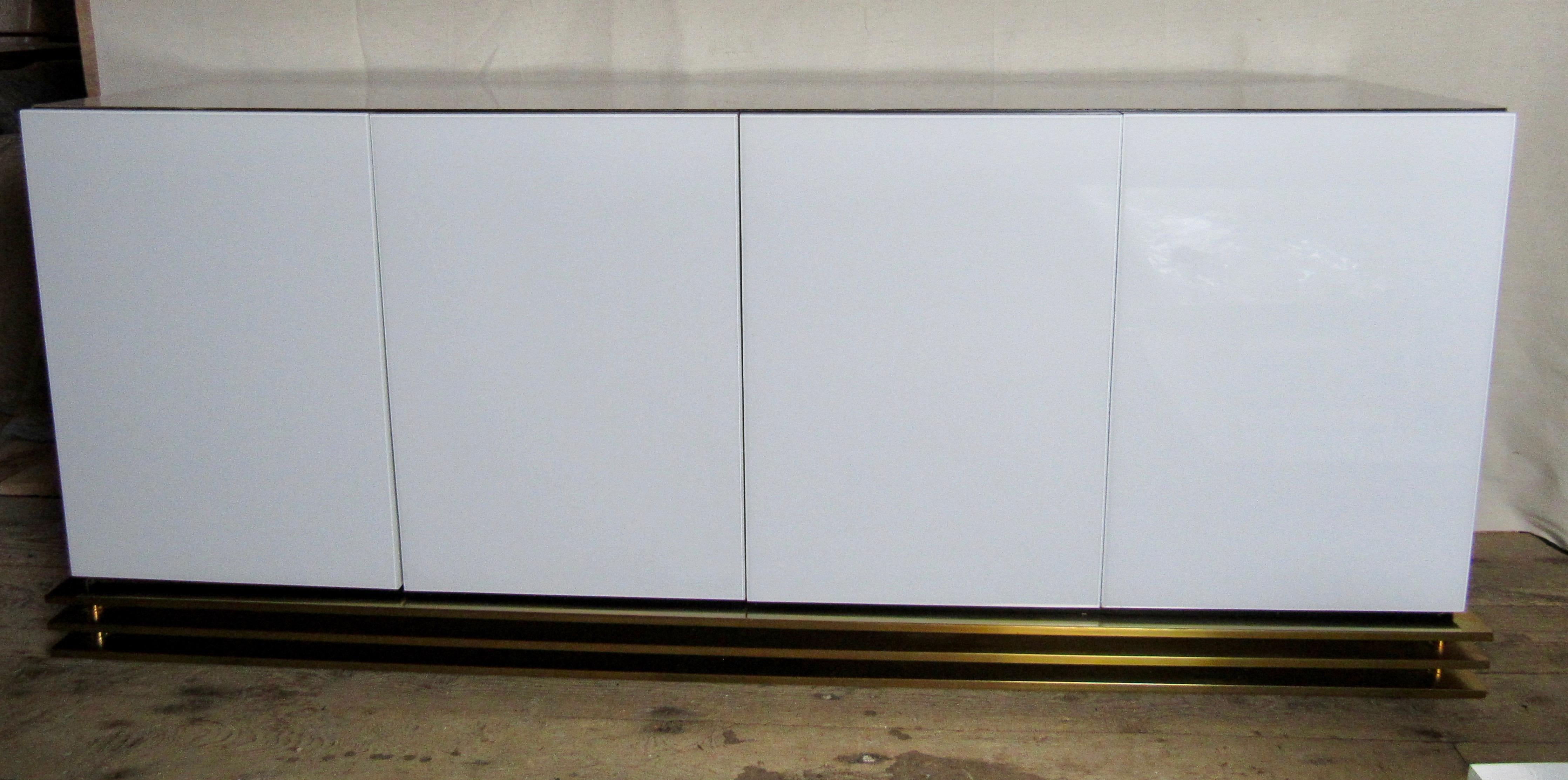Minimalist white Lucite and white Formica four door sideboard credenza setback on a triple banded base. Black interior with two glass shelves. Milo Baughman style design.