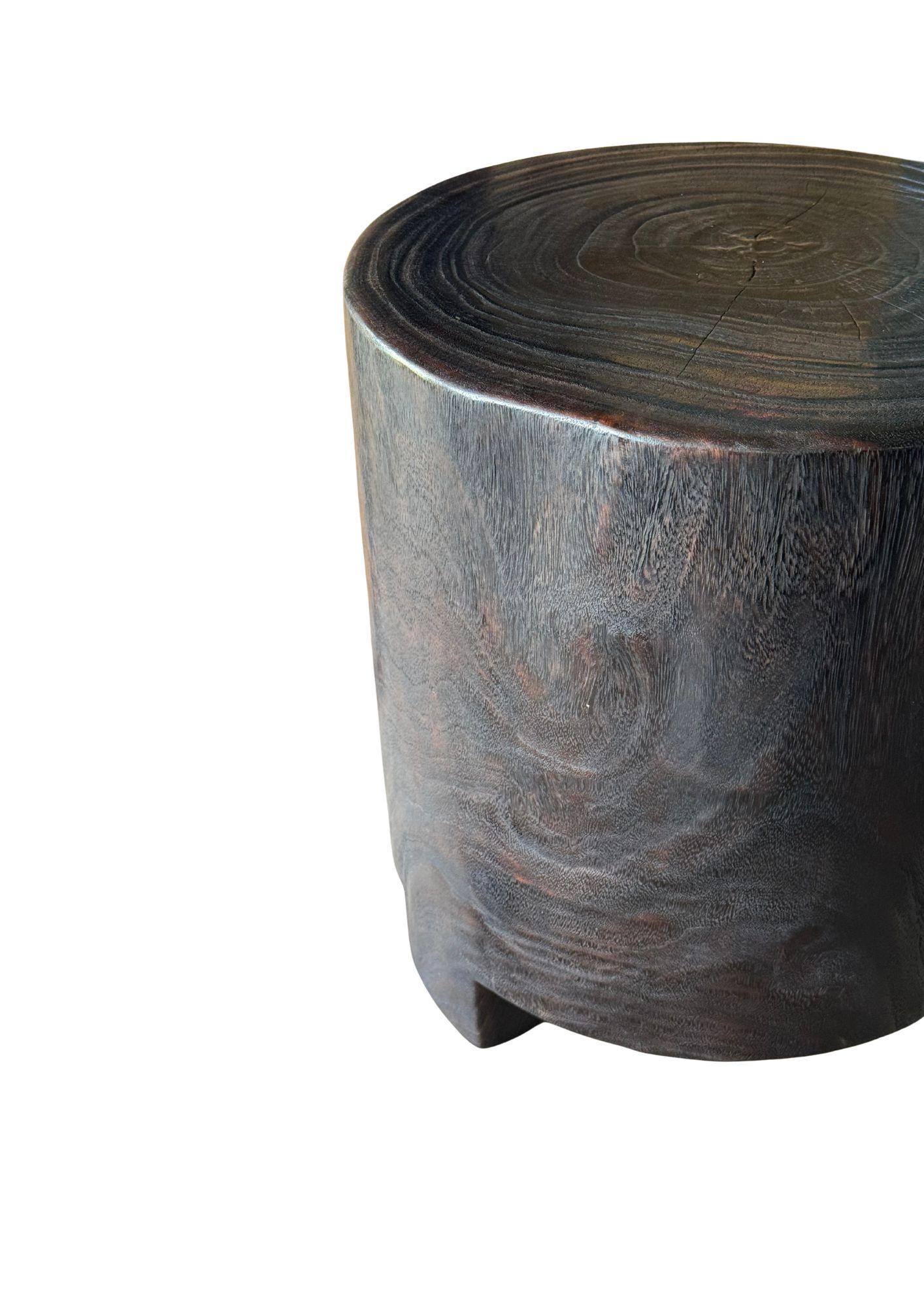 Carved from a single, solid block of suar wood, this sculptural accent table showcases the natural beauty and organic movement of the timber. Its deep espresso finish is achieved through a meticulous multi-stage burning process, enriching the wood’s