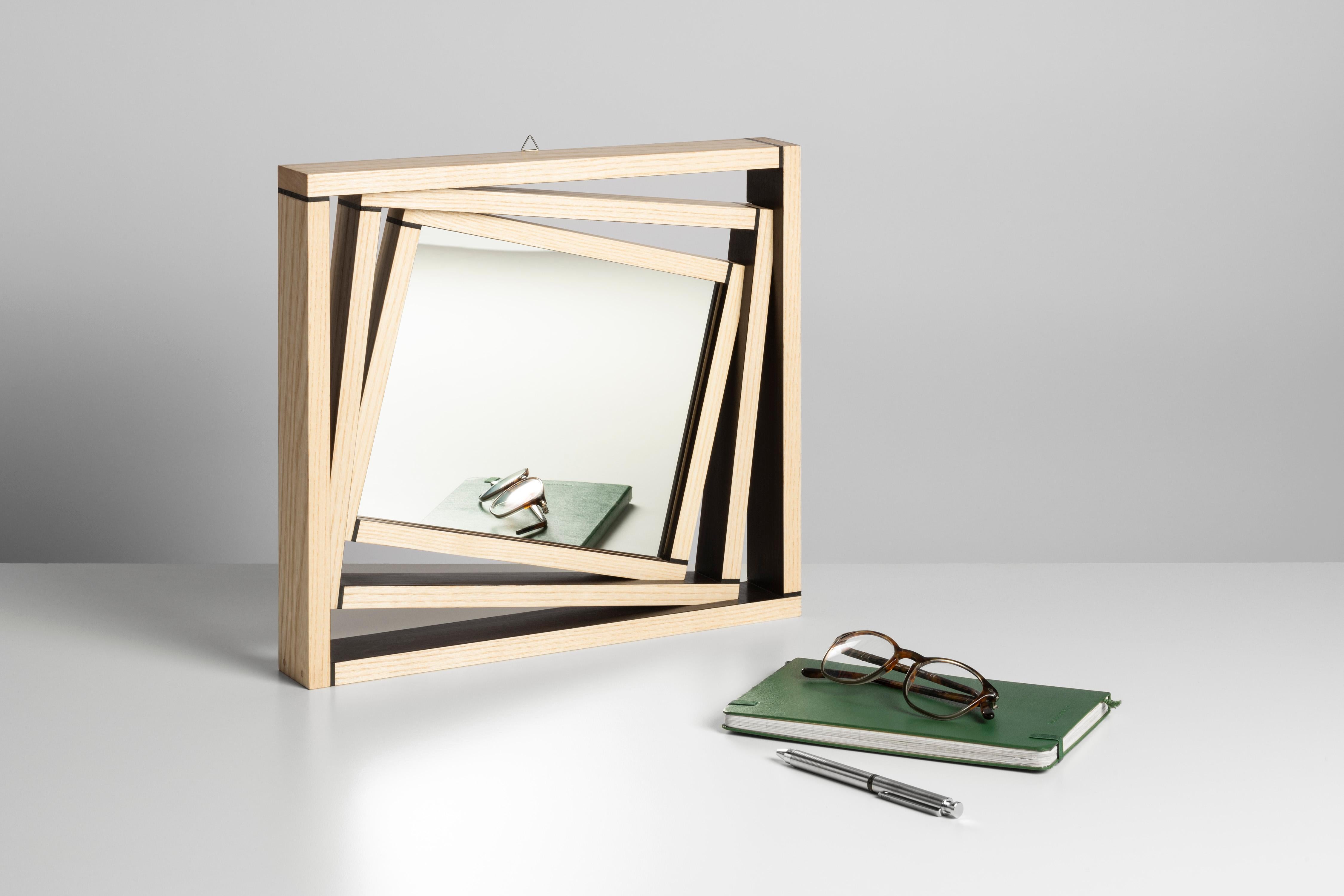 The frame of the mirror is composed of three elements that are progressively tilted and this particular detail gives depth to this minimalist piece made of ebony and ash. Solid ash is a light wood characterized by delicate grain that contrasts with