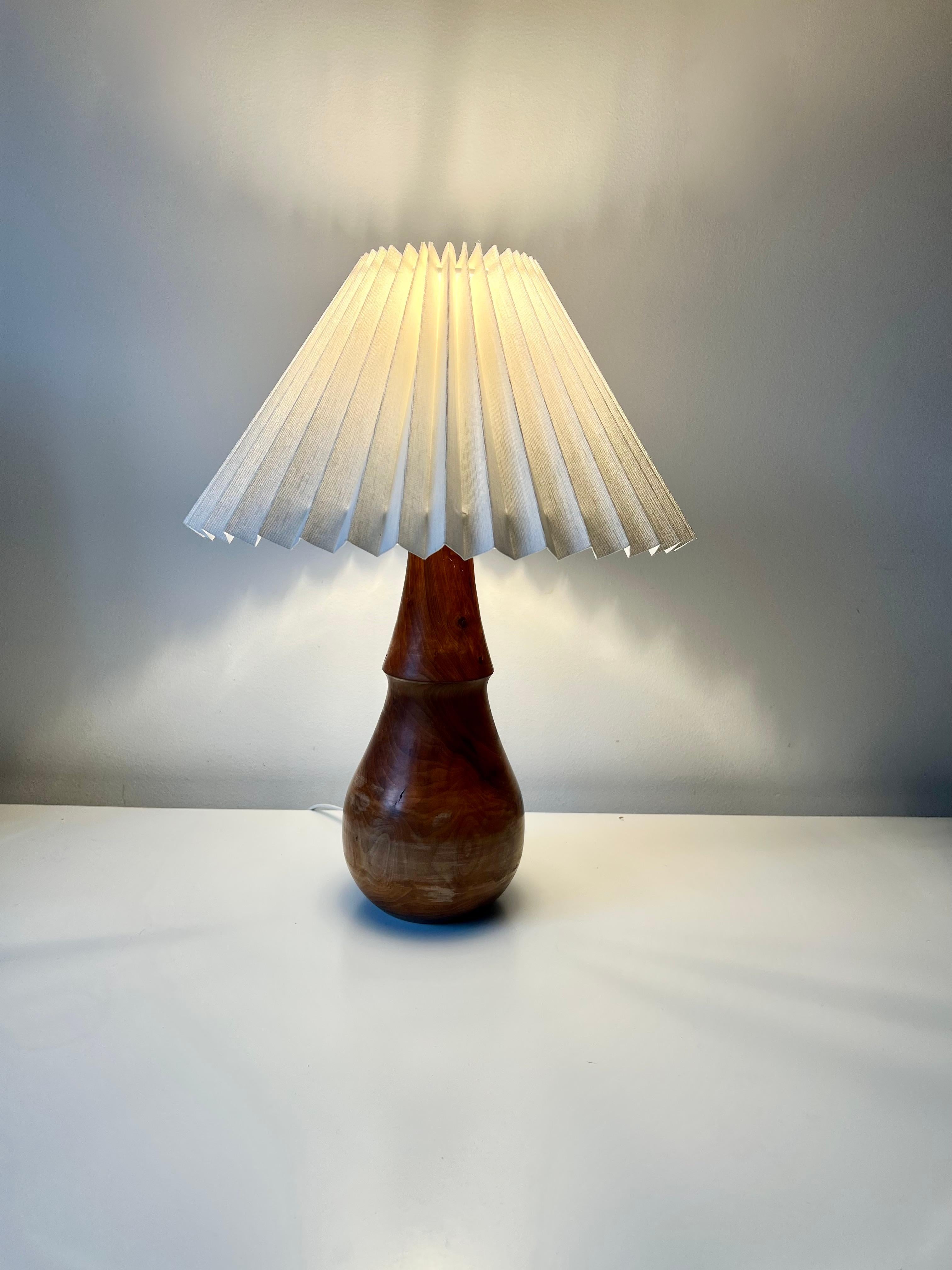 Beautifully simple minimalist vintage turned wood table lamp.

A good sized well proportioned lamp with elegant shape. 

Hand made of a hard wood (fruit wood or olive?) with a nice rich tone.

Supplied with a new linen pleated shade

No damage,