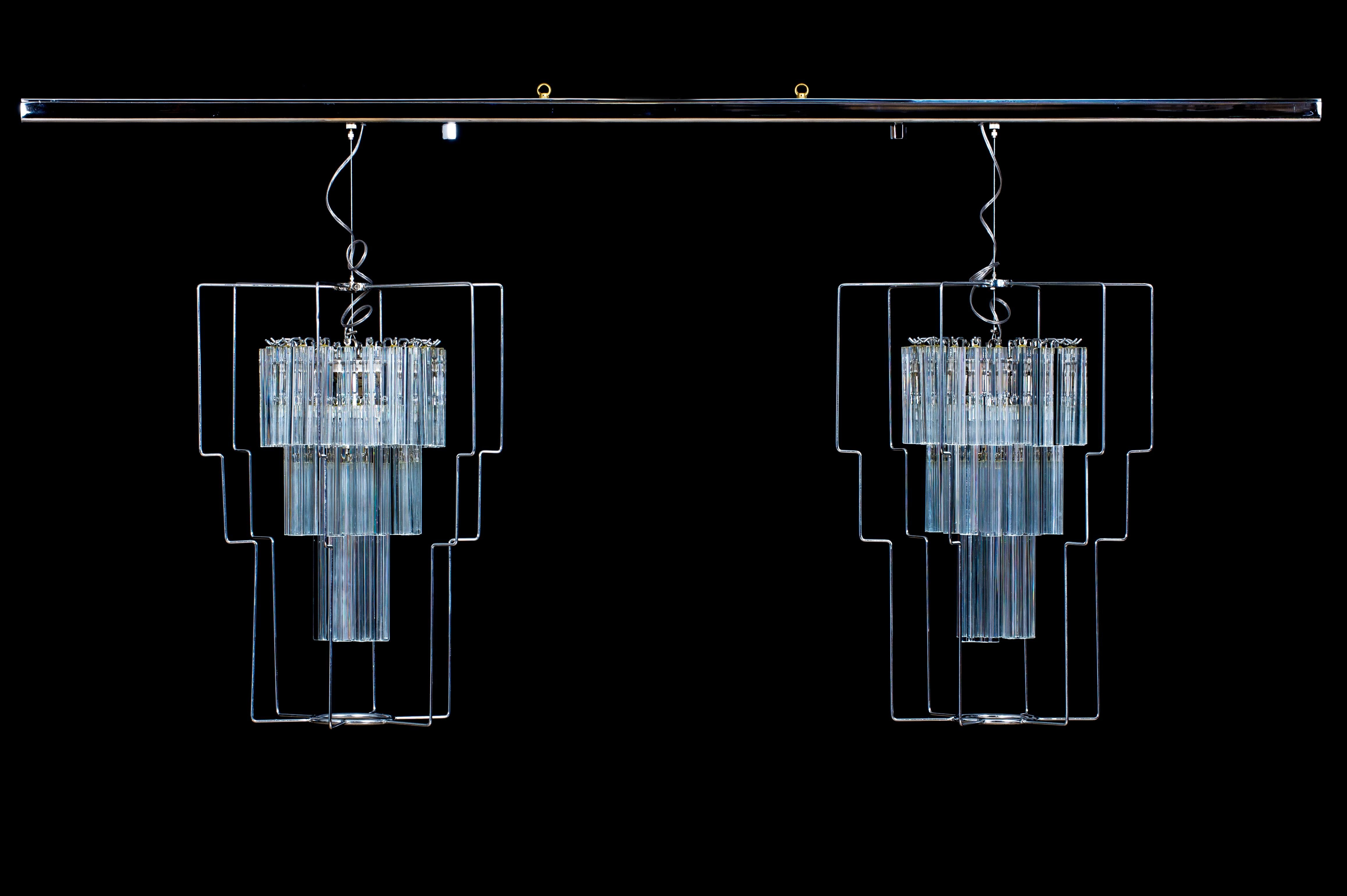 Lustre vénitien minimaliste avec éléments trièdres en verre de Murano, Italie.
Une multitude d'éléments trièdres en verre transparent sont disposés à trois niveaux différents, entourant les 12 lampes, et par leur forme géométrique, diffusent la