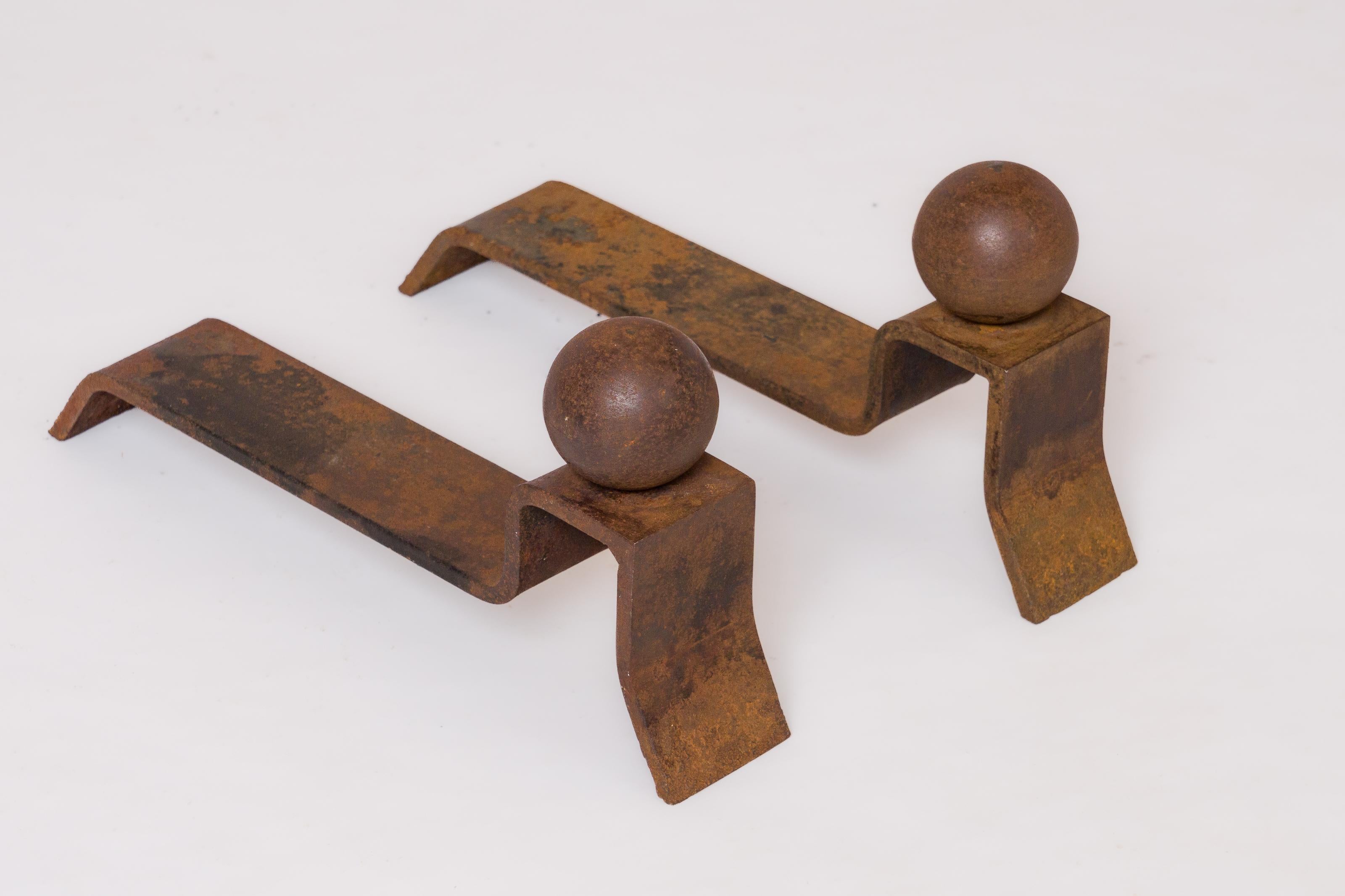 Paire de fer forgé minimaliste de Jacques Adnet présentant une base architecturale surmontée d'un socle.  par une boule de fer. Patine d'origine et oxydation. Peut être poncé sur demande (250 $ de frais supplémentaires).
Ces fers à repasser sont