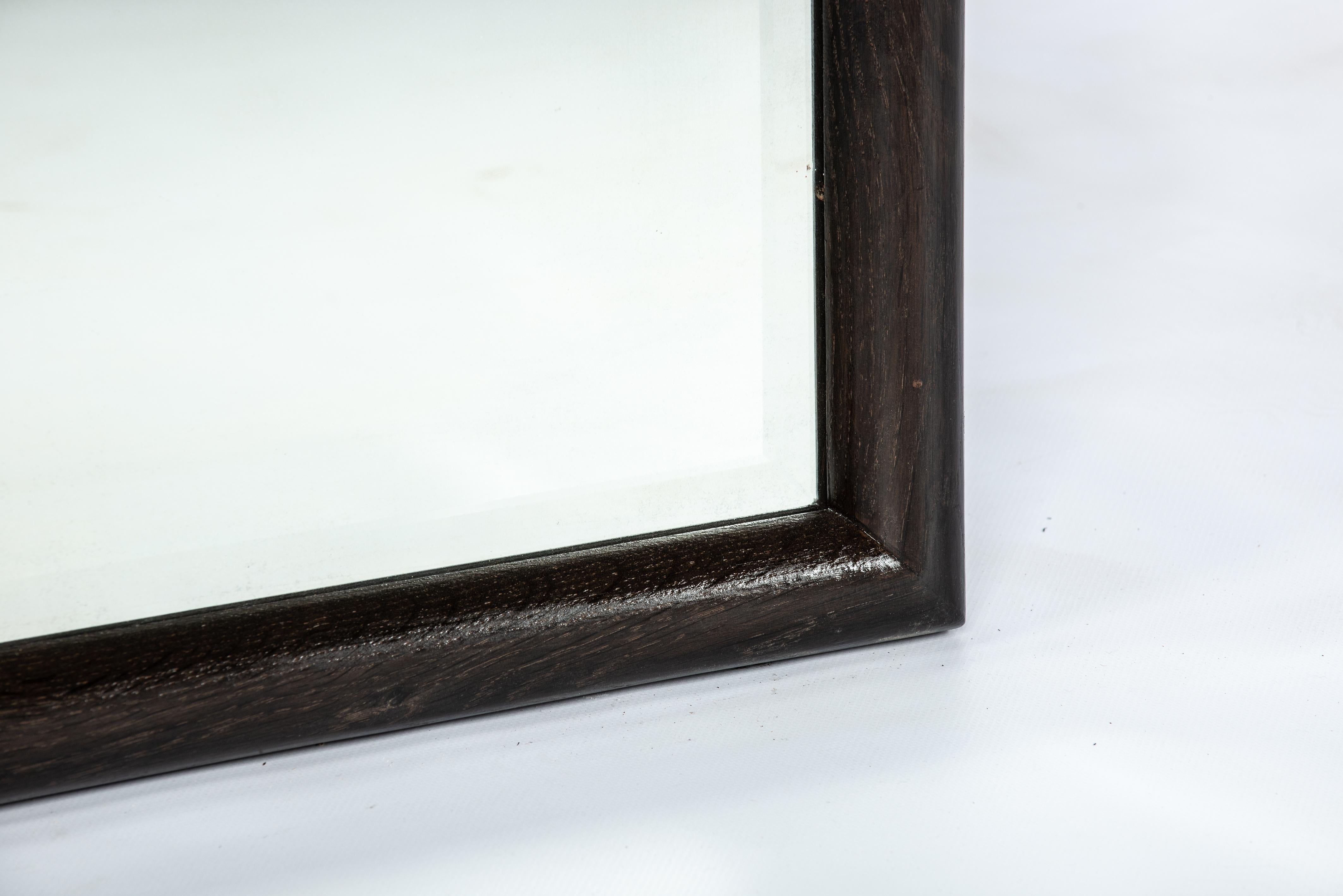 Presenting a stunning antique beveled mirror enclosed in a sleek solid oak frame. The amalgamation of the antique glass and the newly crafted wooden frame exudes elegance. The mirror plate features beveled edges and dates back to around 1880. This