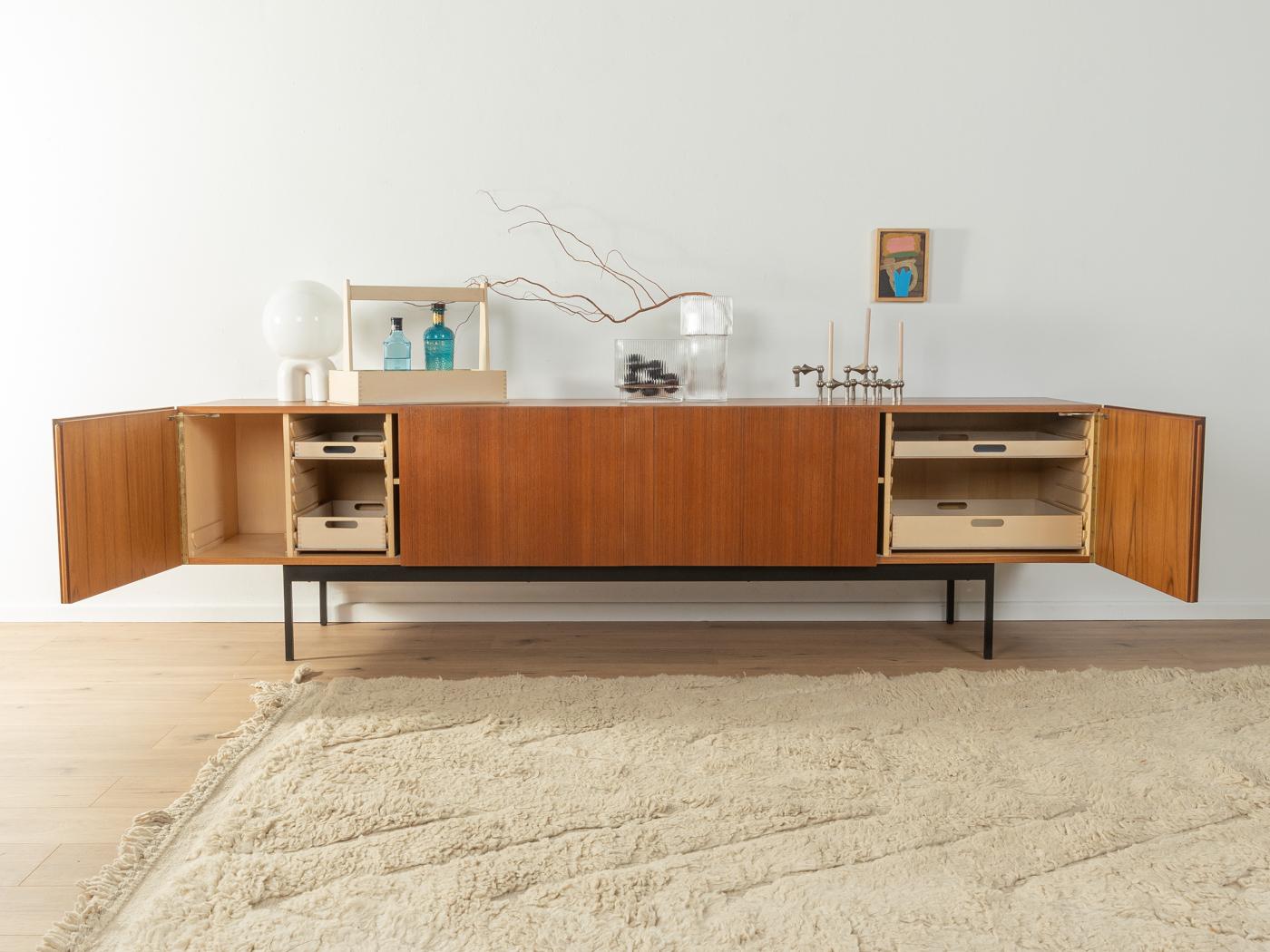 Puristic sideboard from the 1950s by Dieter Wäckerlin for Behr Möbel, model B40. Corpus in teak veneer with four doors, four internal drawers, a bottle tray, two shelves and squared steel feet in black.

Quality Features:
 Accomplished design: