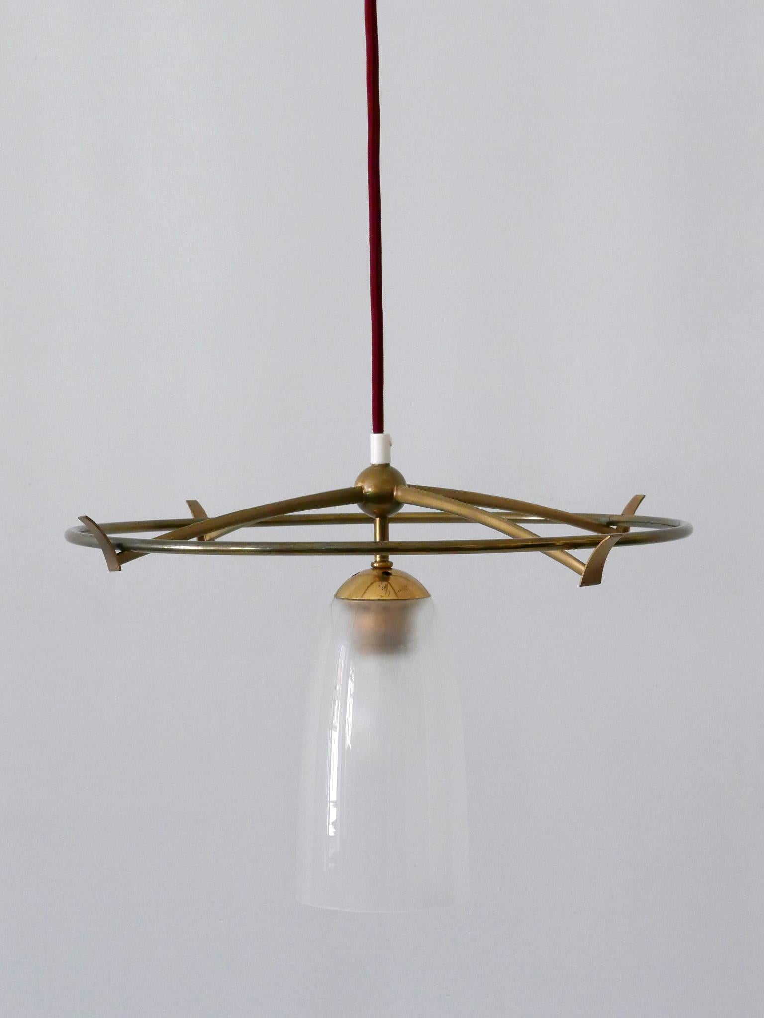 Extrêmement rare et élégante lampe pendante ou lampe à suspendre UFO de l'ère spatiale. Conçu et fabriqué probablement en Allemagne, dans les années 1950.

Réalisée en laiton et en verre laiteux, la lampe est livrée avec un porte-ampoule à vis