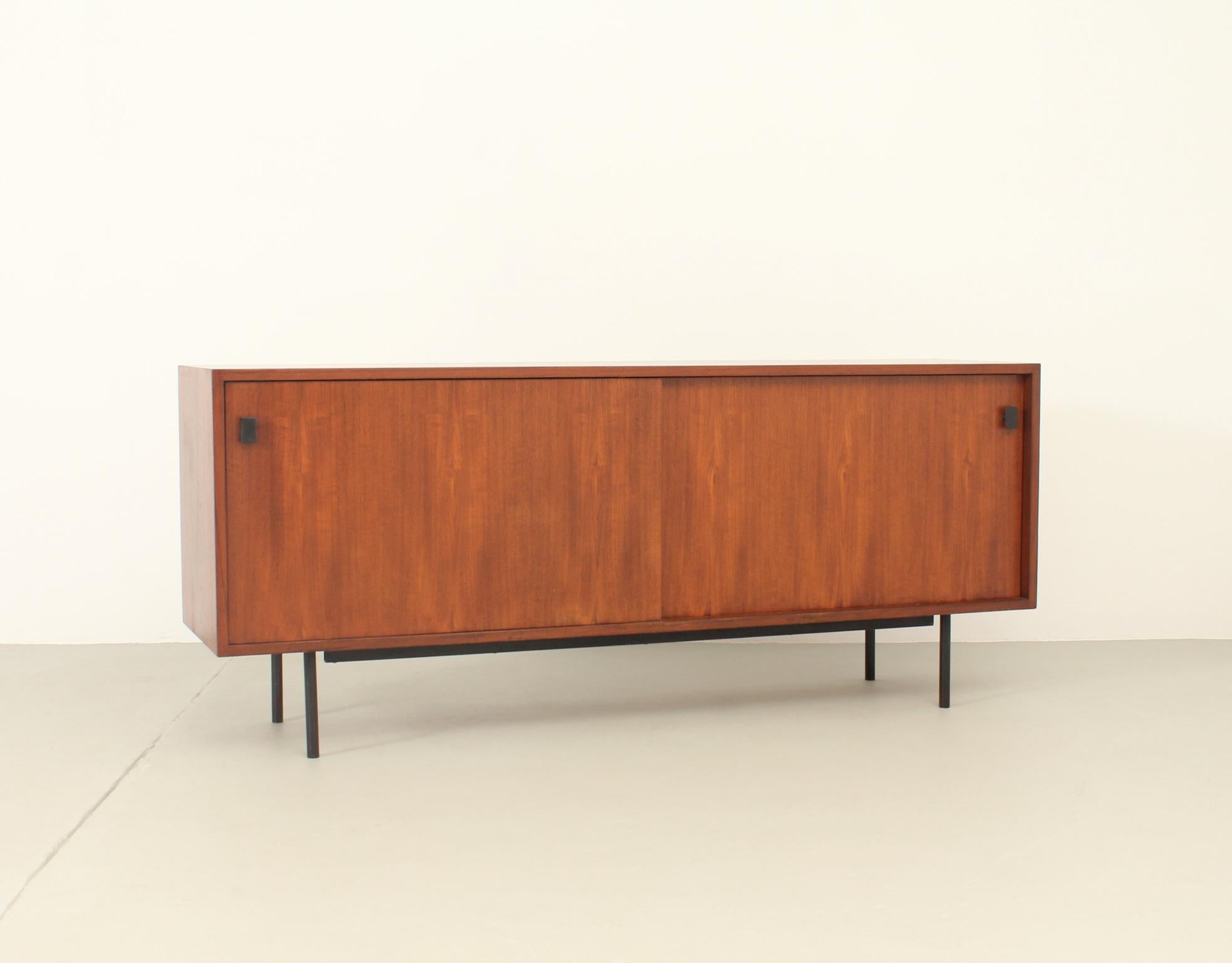 Mid-century sideboard from 1950's probably german or danish design. Minimalistic design with two sliding doors with two small handles in teak wood and black lacquered metal base.
