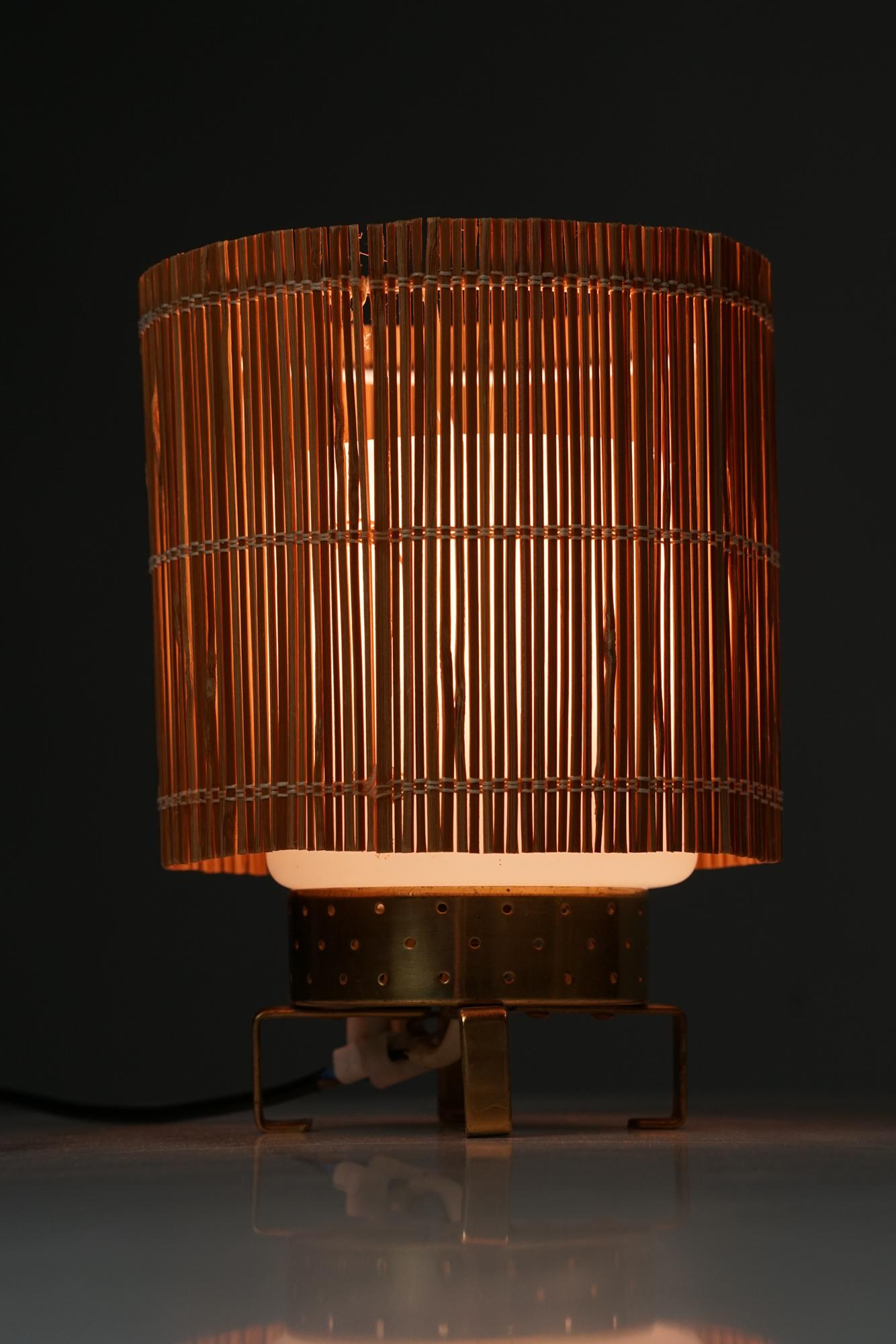 Minimalistic model 61071/1 Idman Oy table lamp from the 1950s. Brass, opaline glass shade with later wooden slat shade. Manufacturer's stamp. Good vintage condition, minor patina and wear consistent with age and use. 
Beautiful Scandinavian Modern