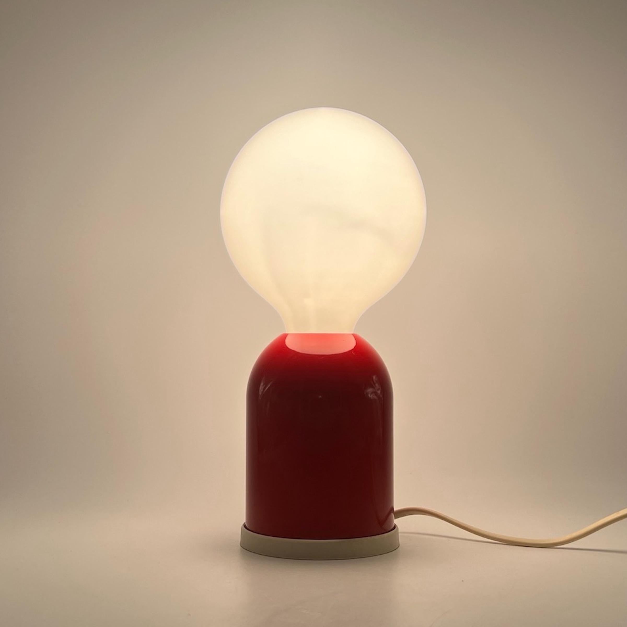 Beautiful patent design lamp with a distinctive antropomophic shape manufactured by Targetti in the 80s.

The base is made of lacquered red metal. The big light bulb (included) evokes the head of a little man. A minimalistic and quirky design