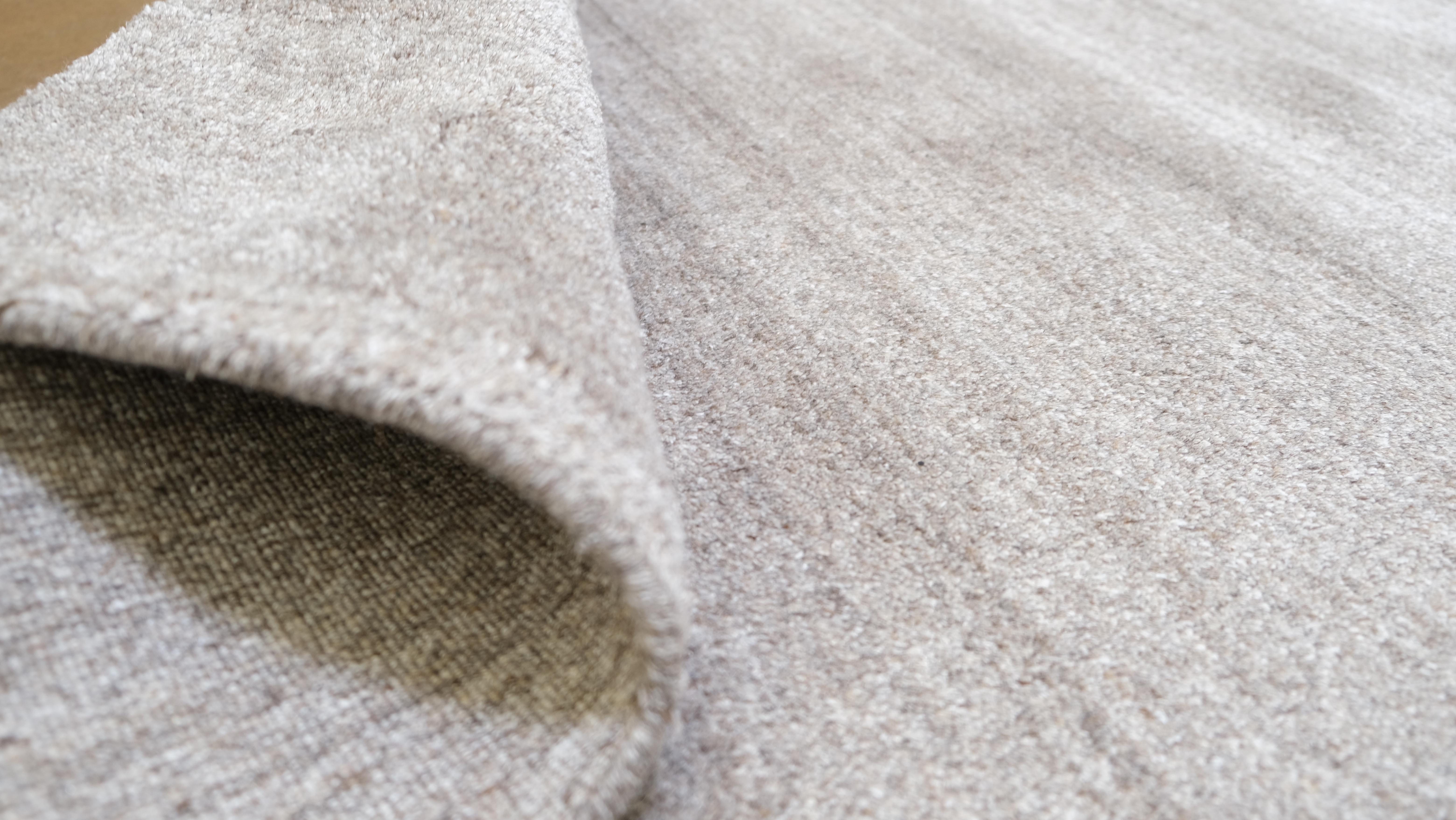 Eleganza per i tuoi interni con questo elegante tappeto in lana e viscosa annodato a mano, caratterizzato da un design minimalista nei toni del grigio-beige. La sobria tavolozza monocromatica aggiunge un tocco raffinato, rendendo questo pezzo ideale