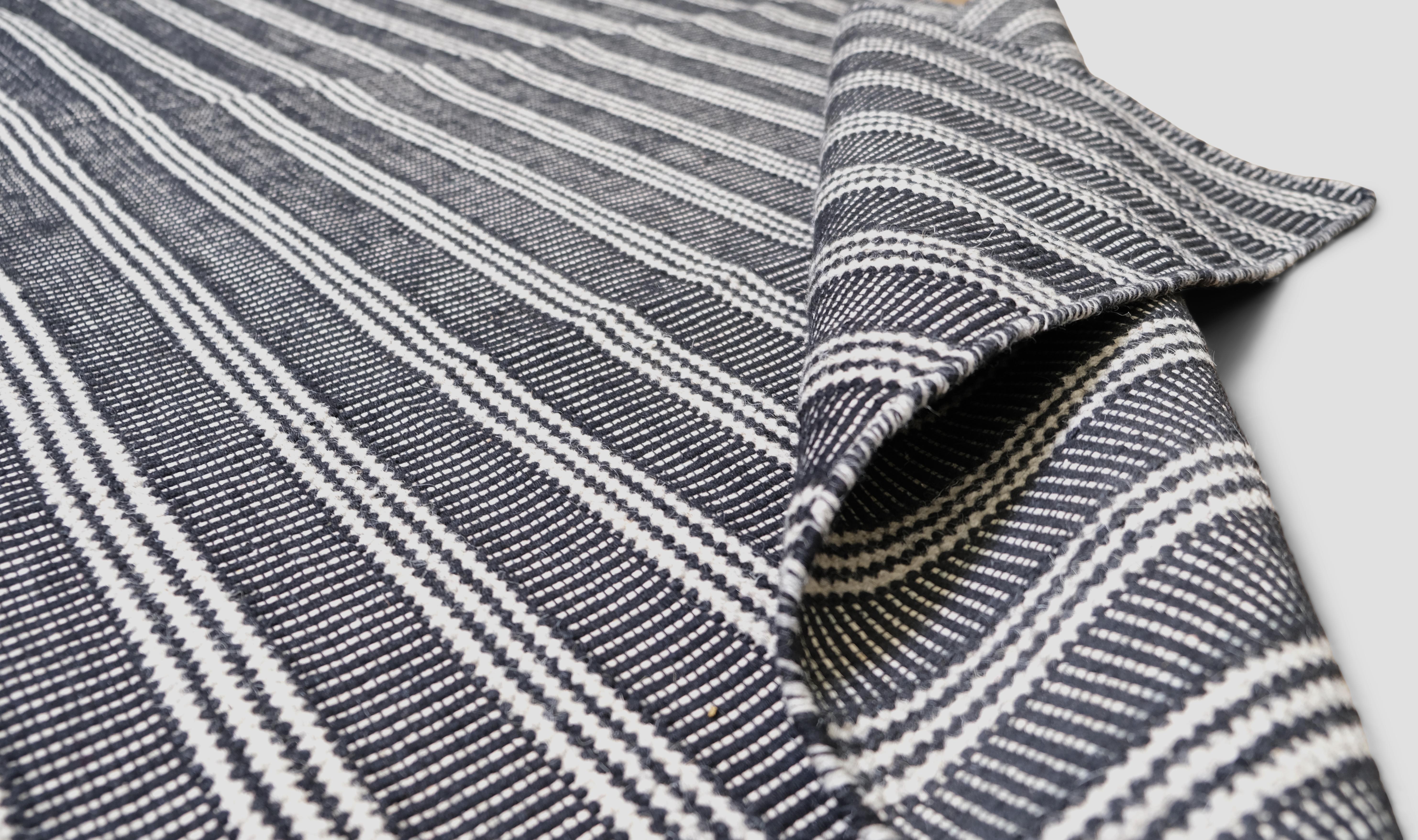  Caratterizzato da un design minimalista a righe in una sofisticata tavolozza bianca e nera, questo tappeto incarna una semplicità senza tempo e un fascino moderno. Le strisce orizzontali creano un senso di struttura e tranquillità, rendendolo una