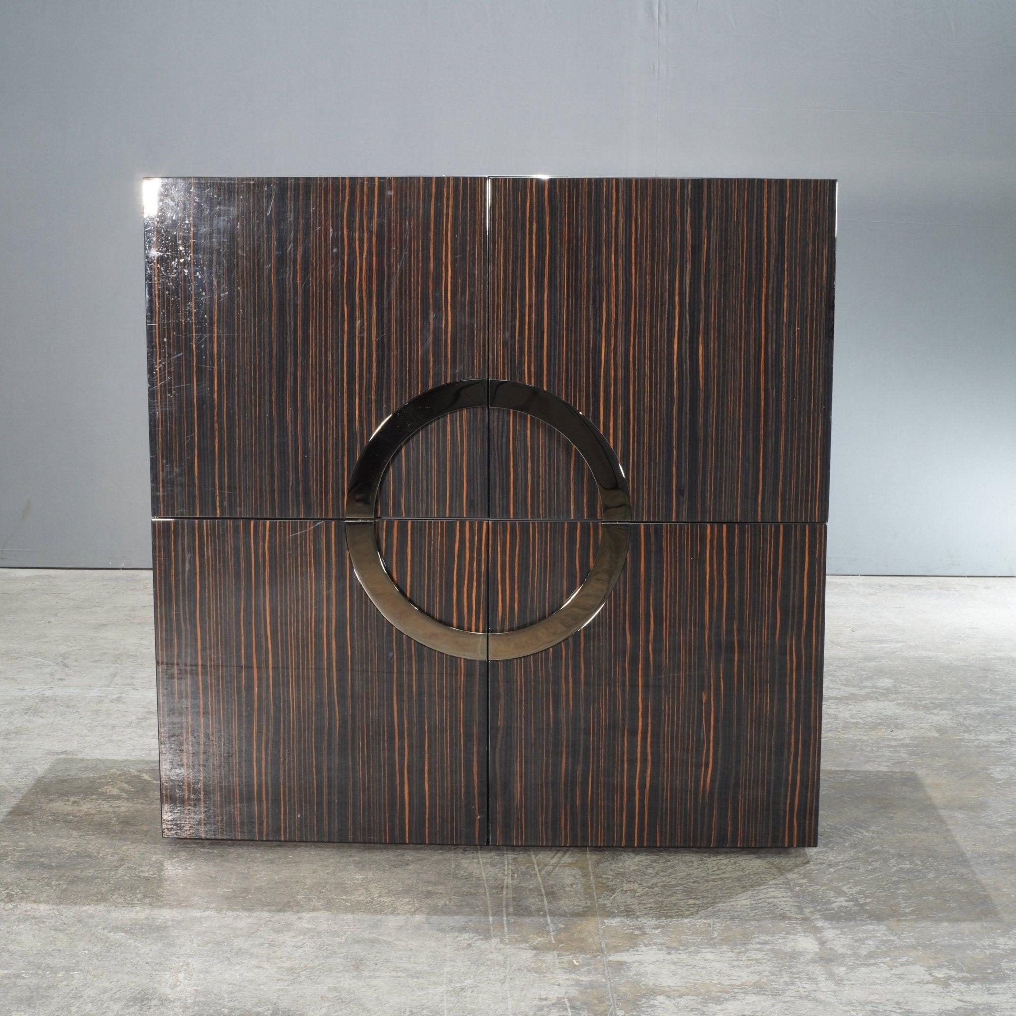 La credenza Minotti Eleg Brown di Rodolfo Dordoni è un pezzo forte dell'eleganza moderna e della maestria artigianale. Rifinita con un'impiallacciatura marrone ricca e lucida con eleganti venature, questa credenza emana lusso. Il manico circolare in