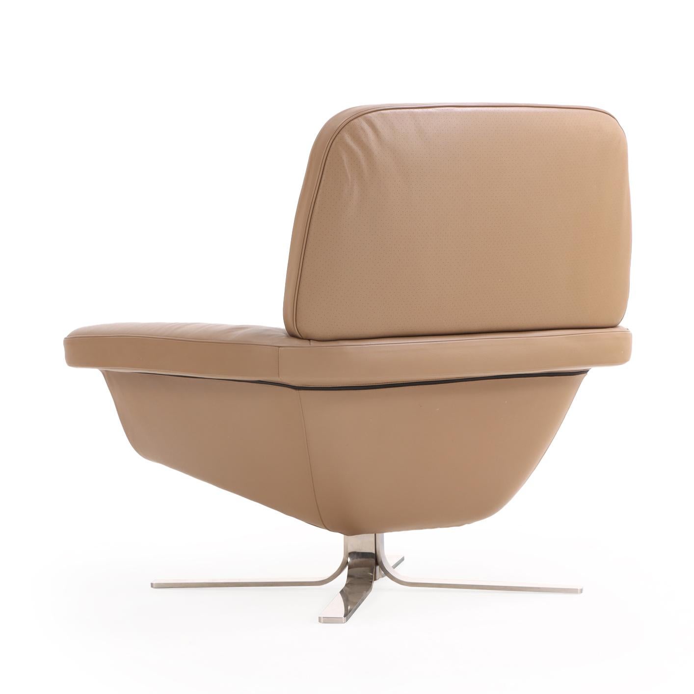 Sedia e pouf Blake Soft di Minotti in stile contemporaneo, rivestiti in morbida pelle marrone e con basi cromate lucide. Gli ampi braccioli e la seduta imbottita della sedia combinano il moderno design italiano con un comfort avvolgente. La sua base