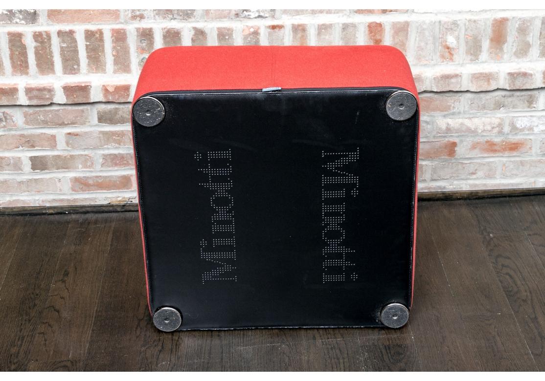 Minotti upholstered square ottoman covered in a red wool/mohair type fabric and resting on flat disk feet. The ottoman has a zippered bottom that allows for removal of the upholstery cover - however, the zipper pull is broken off.

Dimensions: 24
