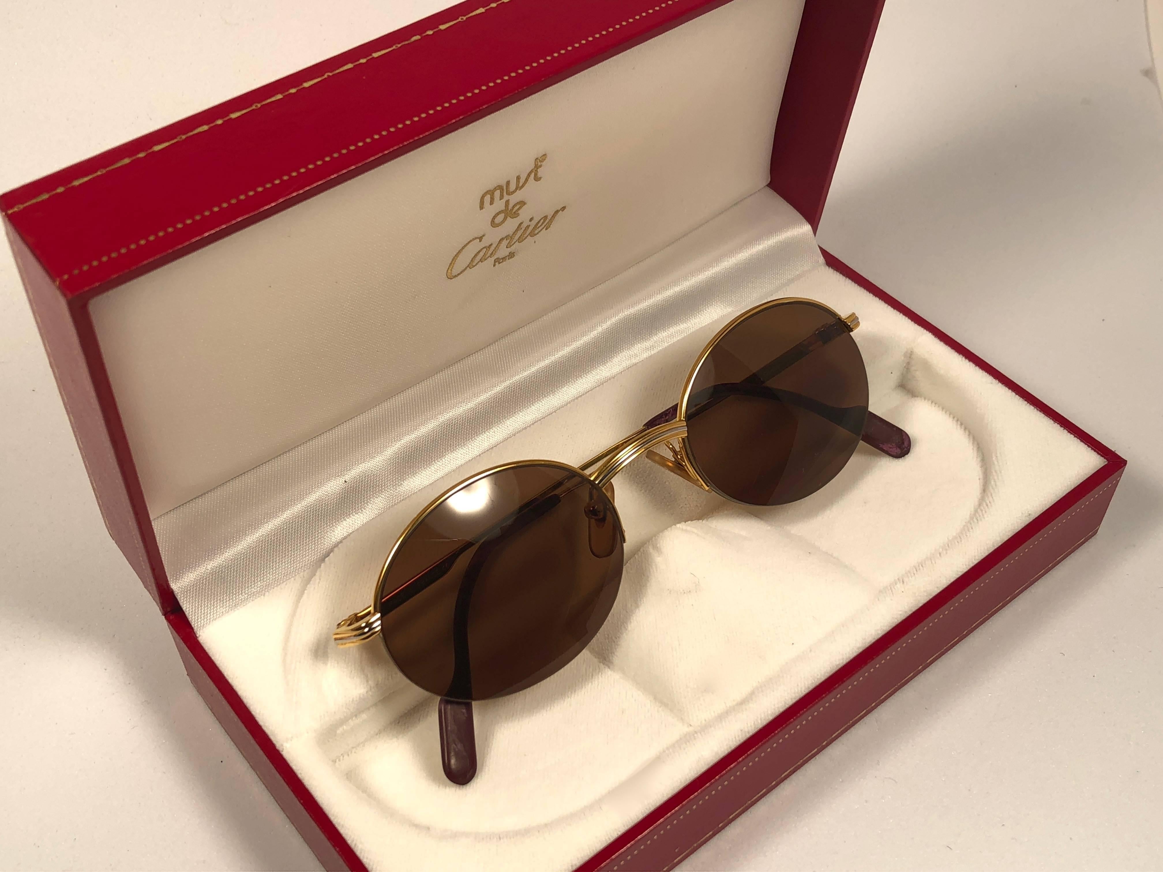 Mint Cartier oval Manhattan sunglasses with brown lenses (uv protection).  All hallmarks. Gold Cartier signs on the ear paddles. 
Both arms sport the knot from Cartier on the temple. These are like a pair of jewels on your nose. 

Please notice this
