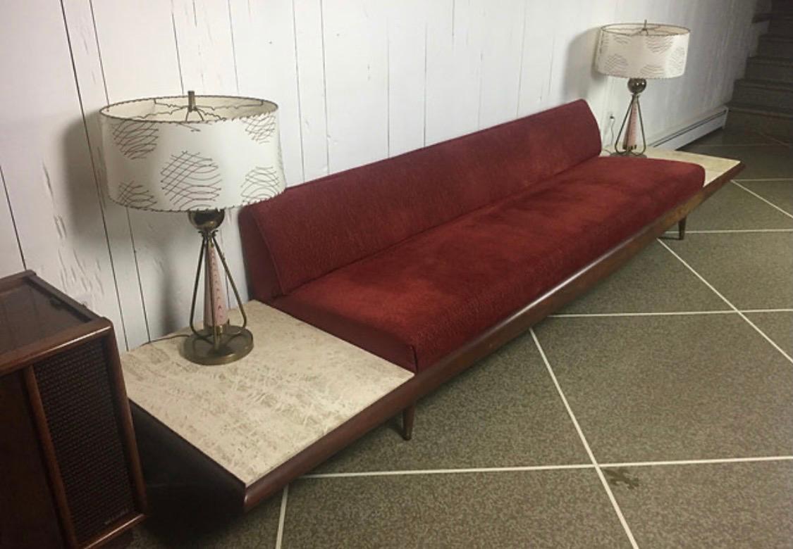 Authentic Adrian Pearsall pieces are some of his most dramatic creations. They also need space! This extra-large Pearsall masterpiece features built-in travertine end tables and matching table lamps. The piece has been reupholstered in a brick red