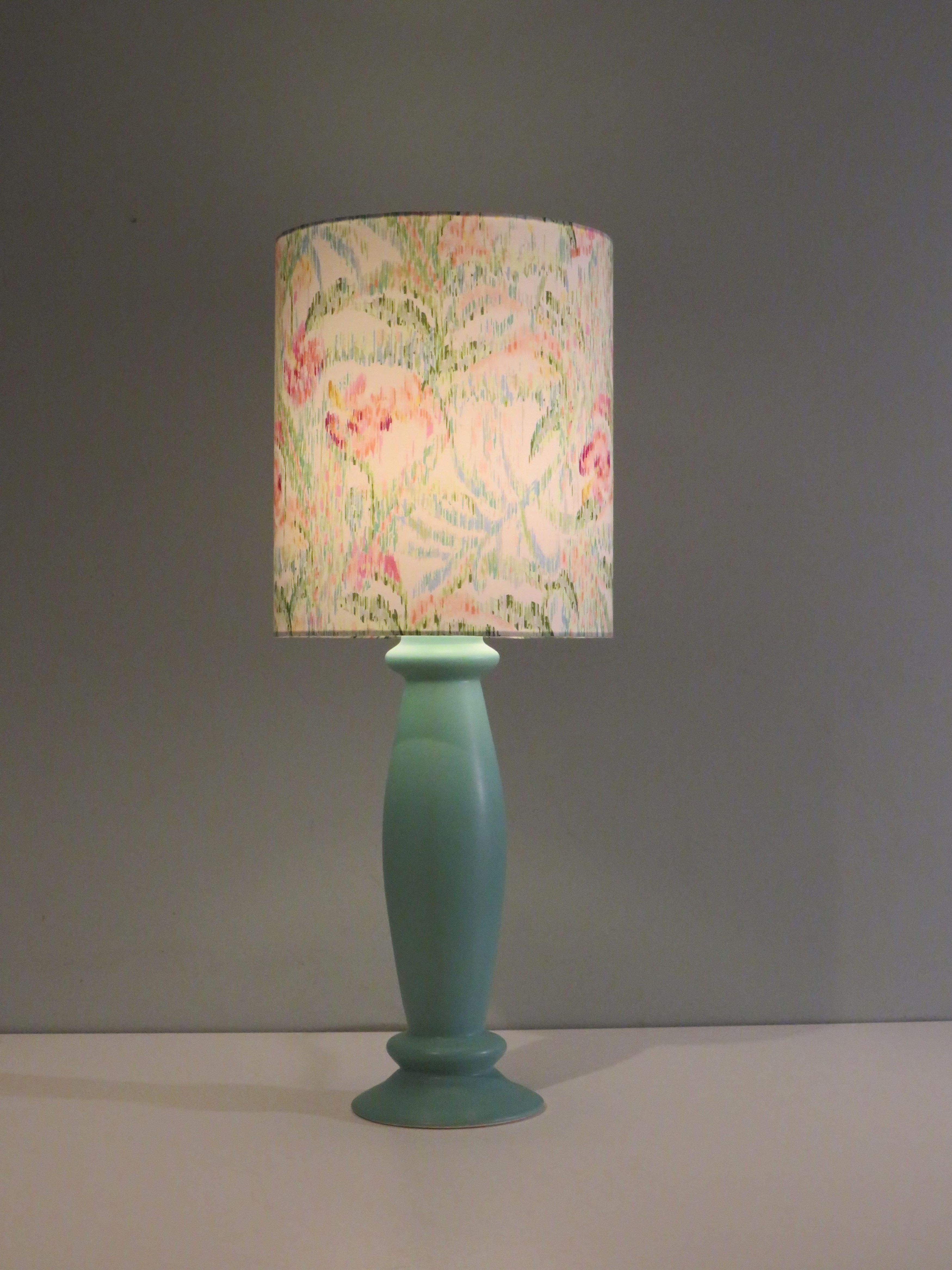 Der Lampenfuß hat eine matte mintgrüne Glasur und eine schlanke Form.
Die Tischlampe hat einen professionell handgefertigten, individuellen Lampenschirm aus feiner Baumwolle mit einem floralen Muster in sanften Farben.
Die Tischleuchte hat ein