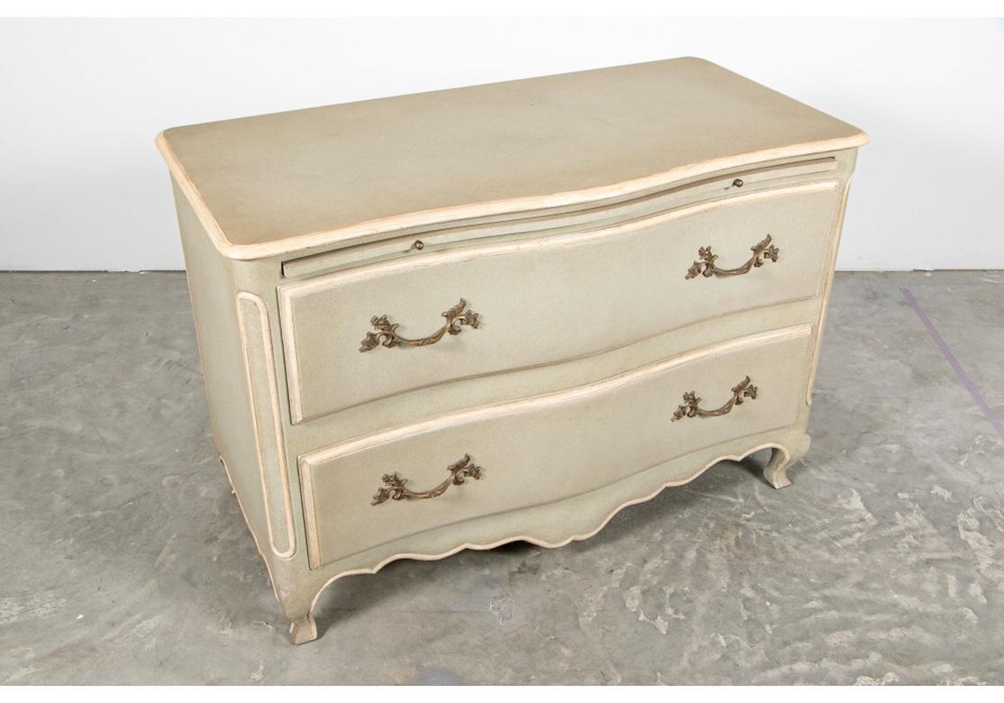 Vintage commode in a textured pale mint green paint with off-white antiqued trim. Two long drawers with fine brass leafy pulls and a painted return pull below the top. The shared skirt raised on cabriole legs.
Measures: Length 46