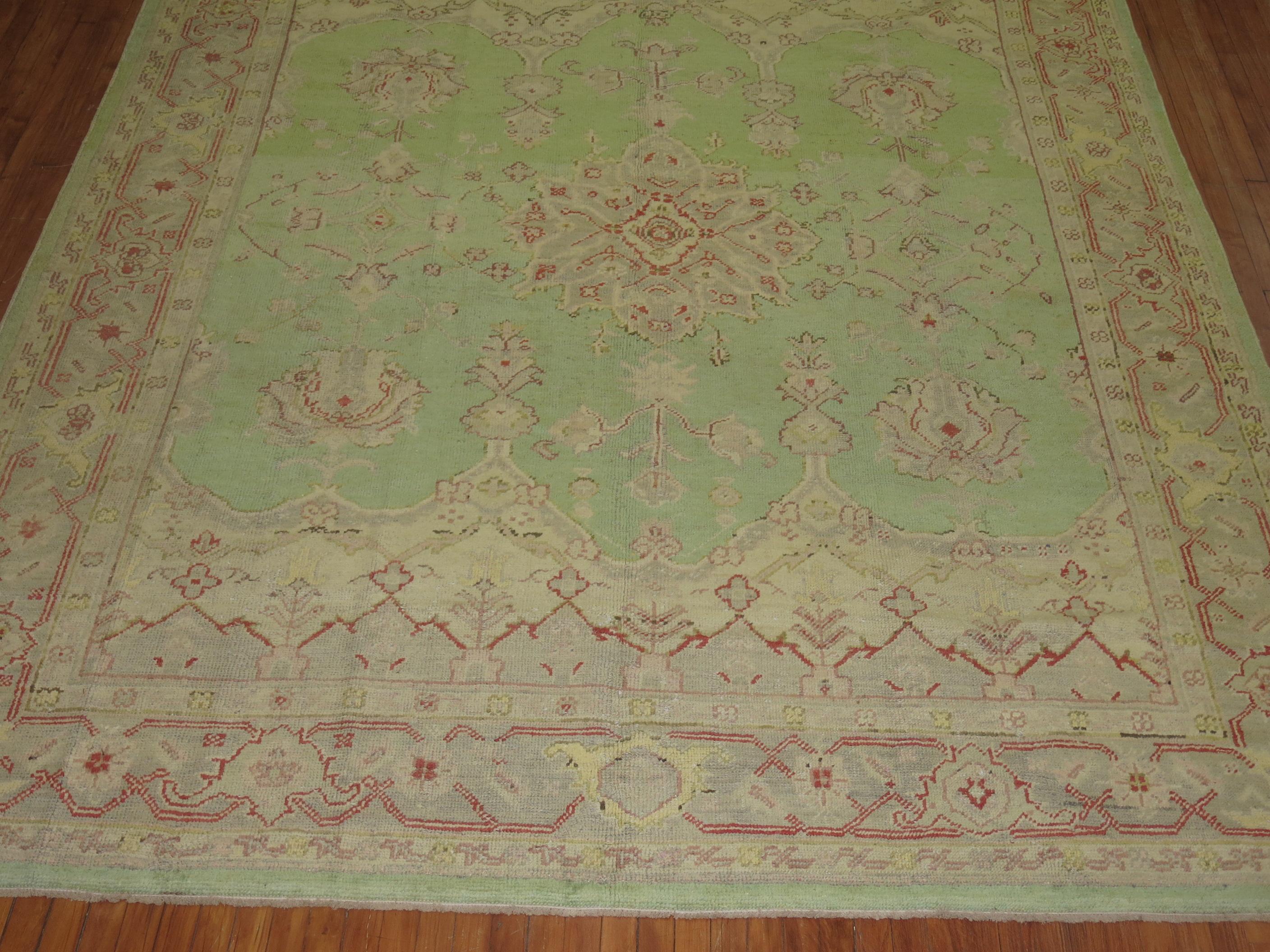An early 20th-century Turkish Oushak with a pistachio green field, gray border accents in pink, soft yellow and red

Measures: 9 x 11'5
