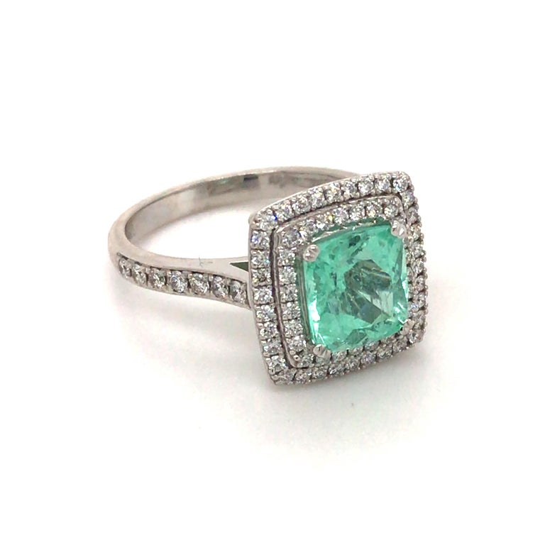 This cushion cut mint green tourmaline is surrounded by a double halo of grain set round brilliant cut diamonds, extending down the shoulders and set in 18ct white gold. 

Mint Tourmaline - 1.89ct 
                           - 7.72 x 7.10mm 

Round