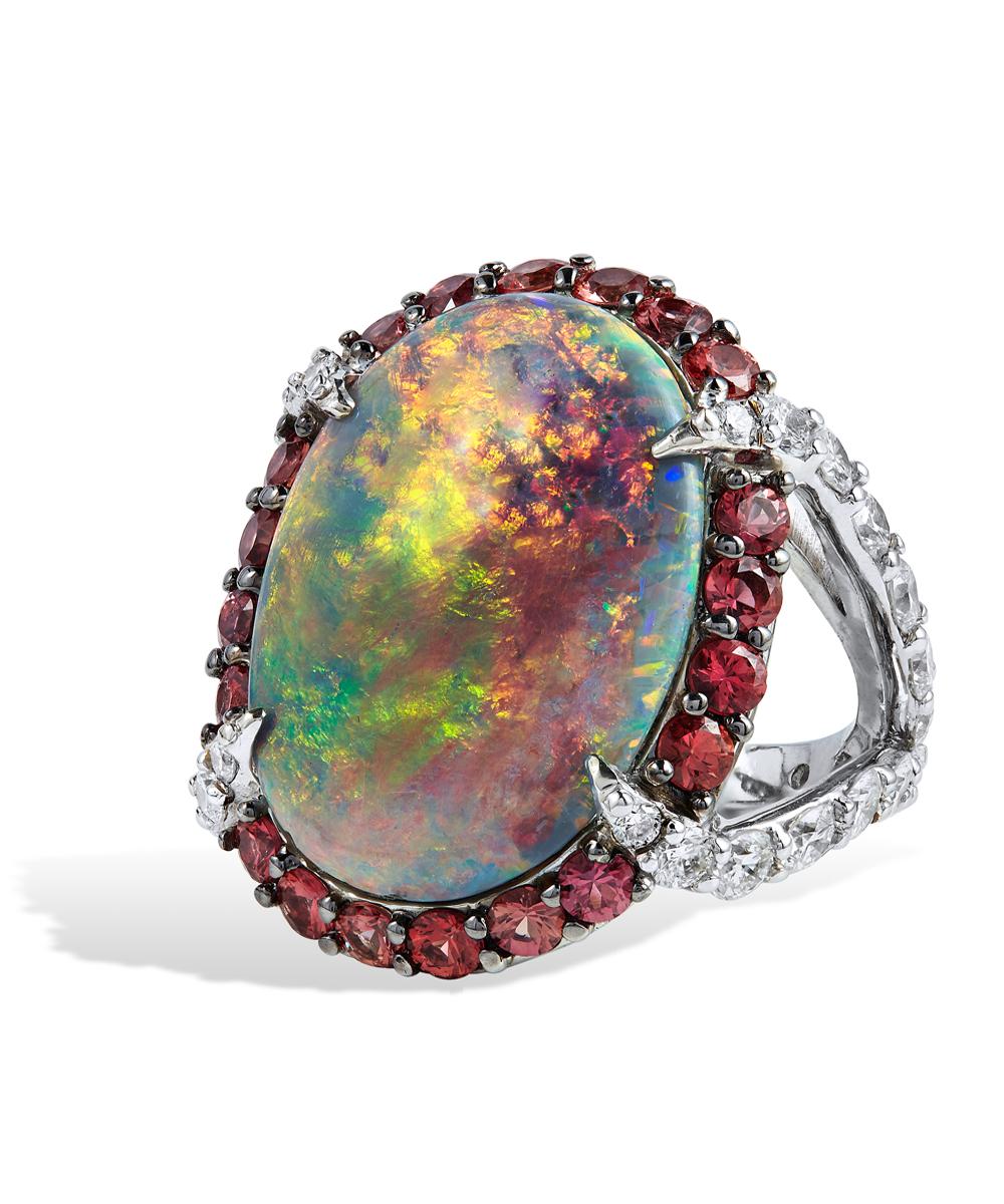 MIntabie opal with flashes of green orange blue and yellow.  This oval shaped stone is a statement ring set with Approx. 2,70 CTS of brilliant cut orange sapphires -bht- and accented by four white pave set diamond prongs that have over four carats