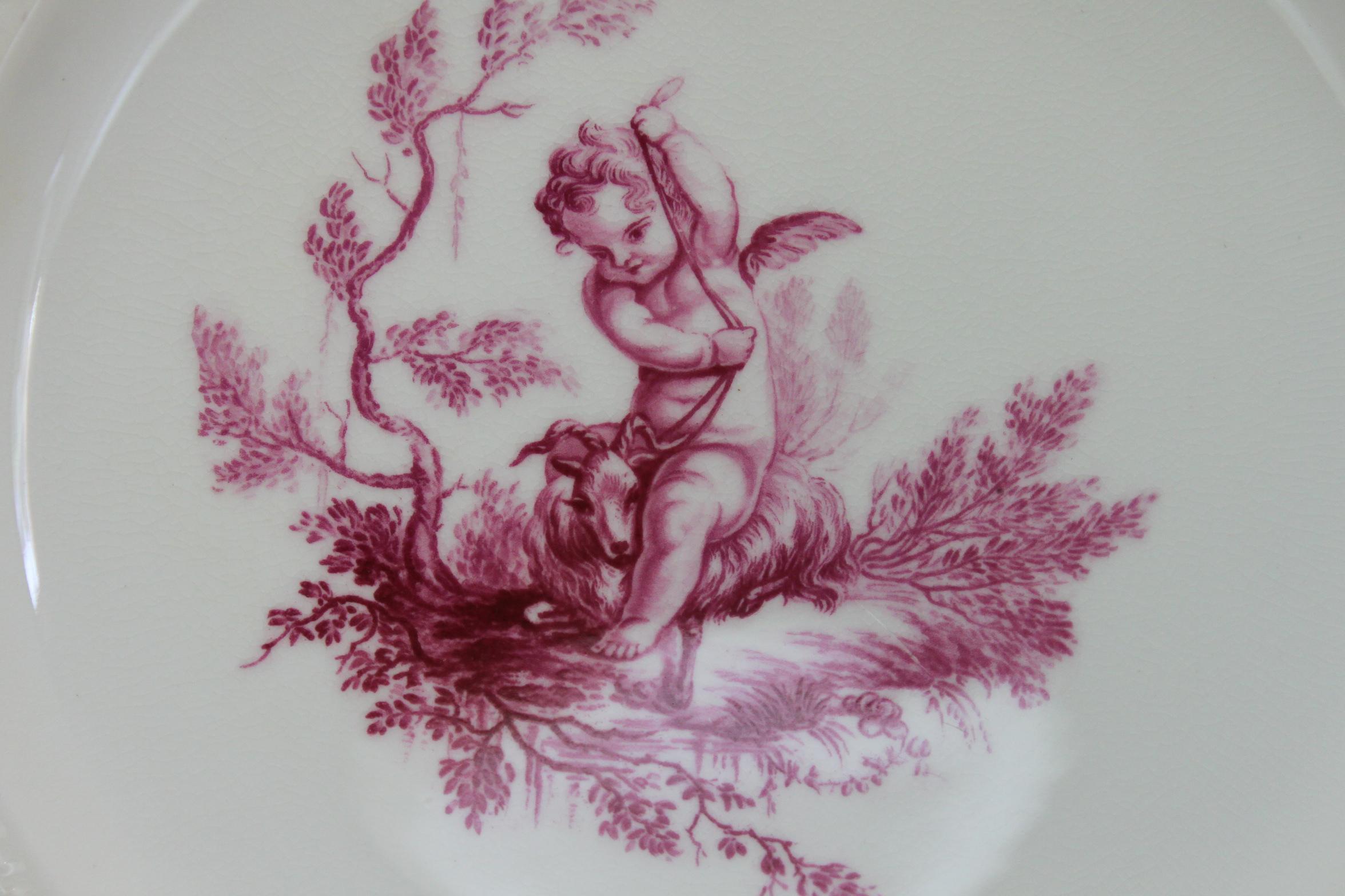 This Minton plate is decorated very simply with a central hand coloured transfer print of a cherub in puce (pattern G1533) The outer rim features a very fine basket weave moulding and the edge is finished with gilding. It was made in 1874 for the