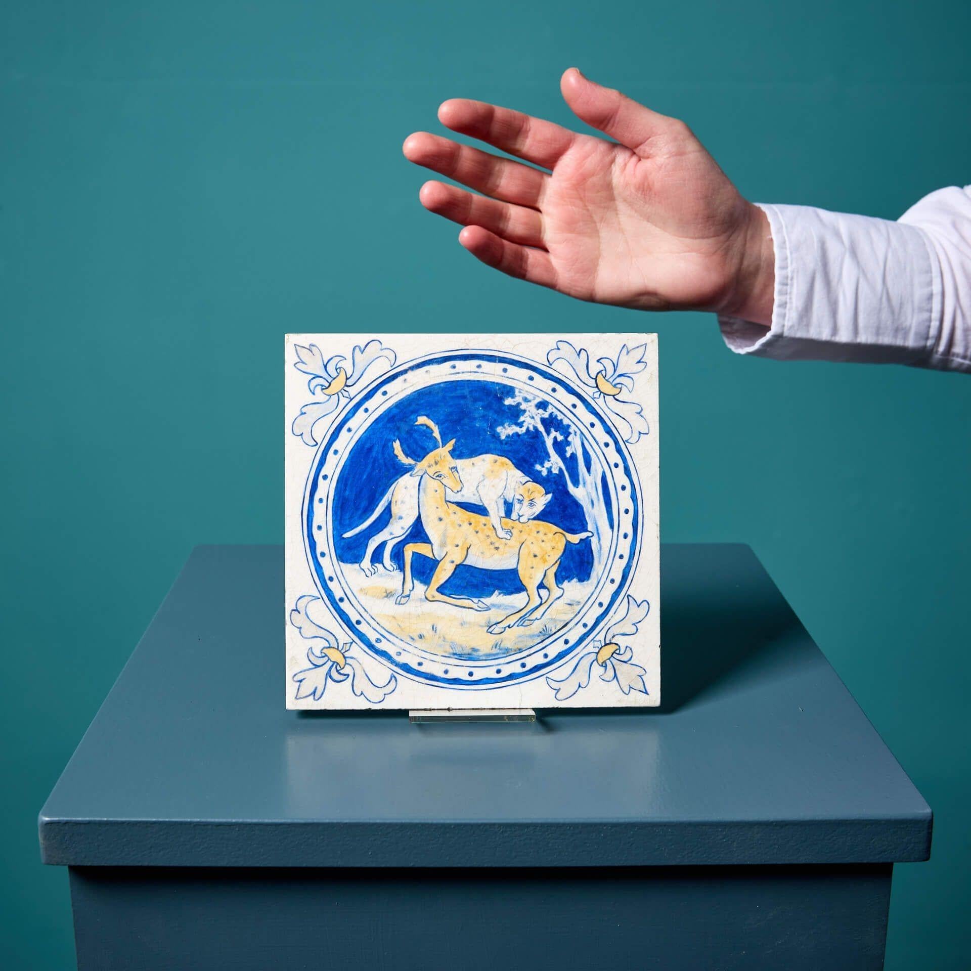Un carreau de porcelaine antique de 6 pouces, pressé par la poussière, de Minton & Co. (estampillé), émaillé et peint à la main avec un rondeau représentant un léopard se jetant sur un cerf dans des tons bleus et jaunes ocre vibrants sur un