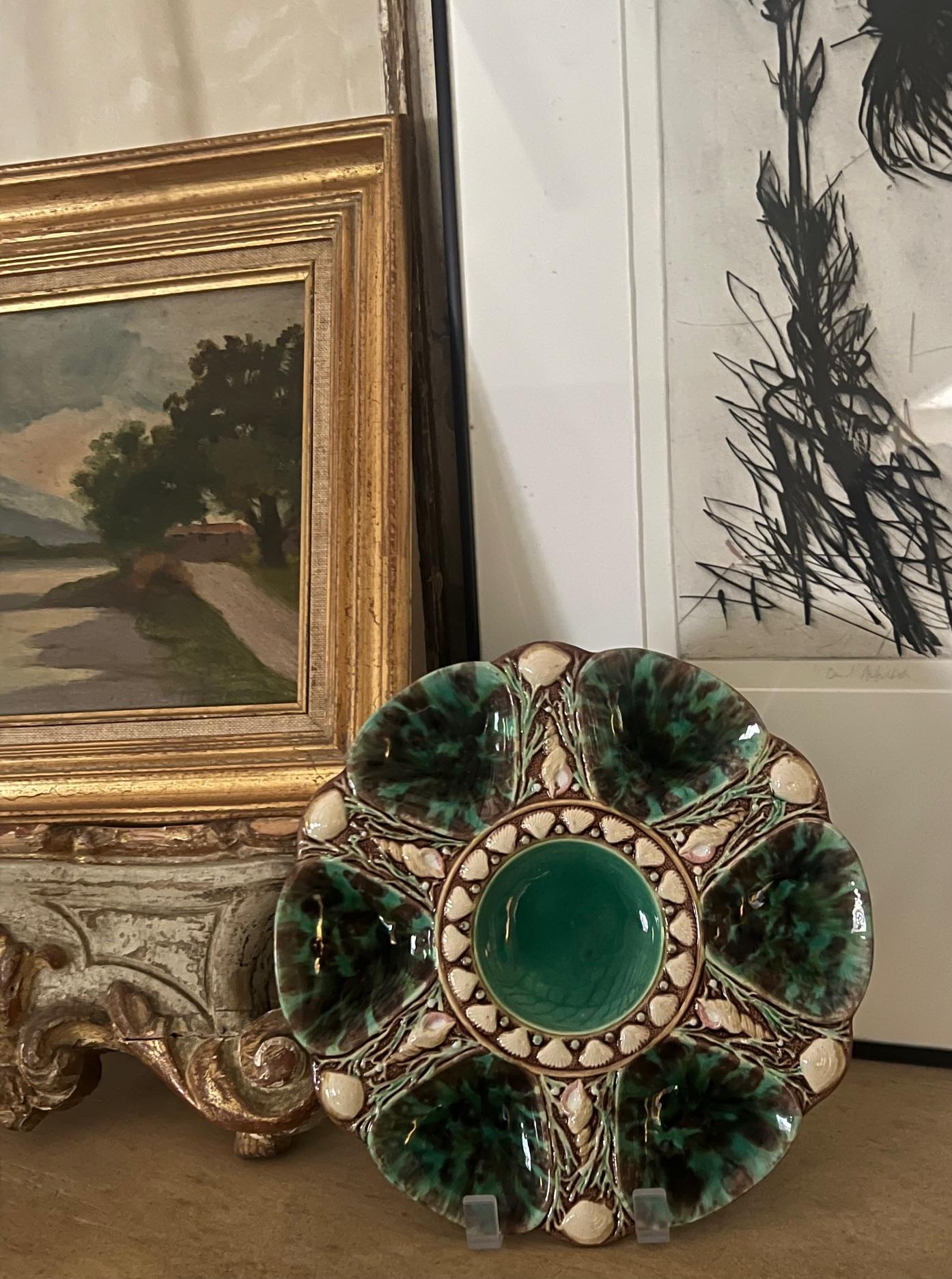 Smaragdgrüner Majolikateller, hergestellt von Minton in England im Jahr 1873. Die Austernplatte hat sechs Vertiefungen und ist von Algen und Muscheln umgeben. Die mittlere Vertiefung kann für Zitronenspalten oder eine Austernminette verwendet werden.