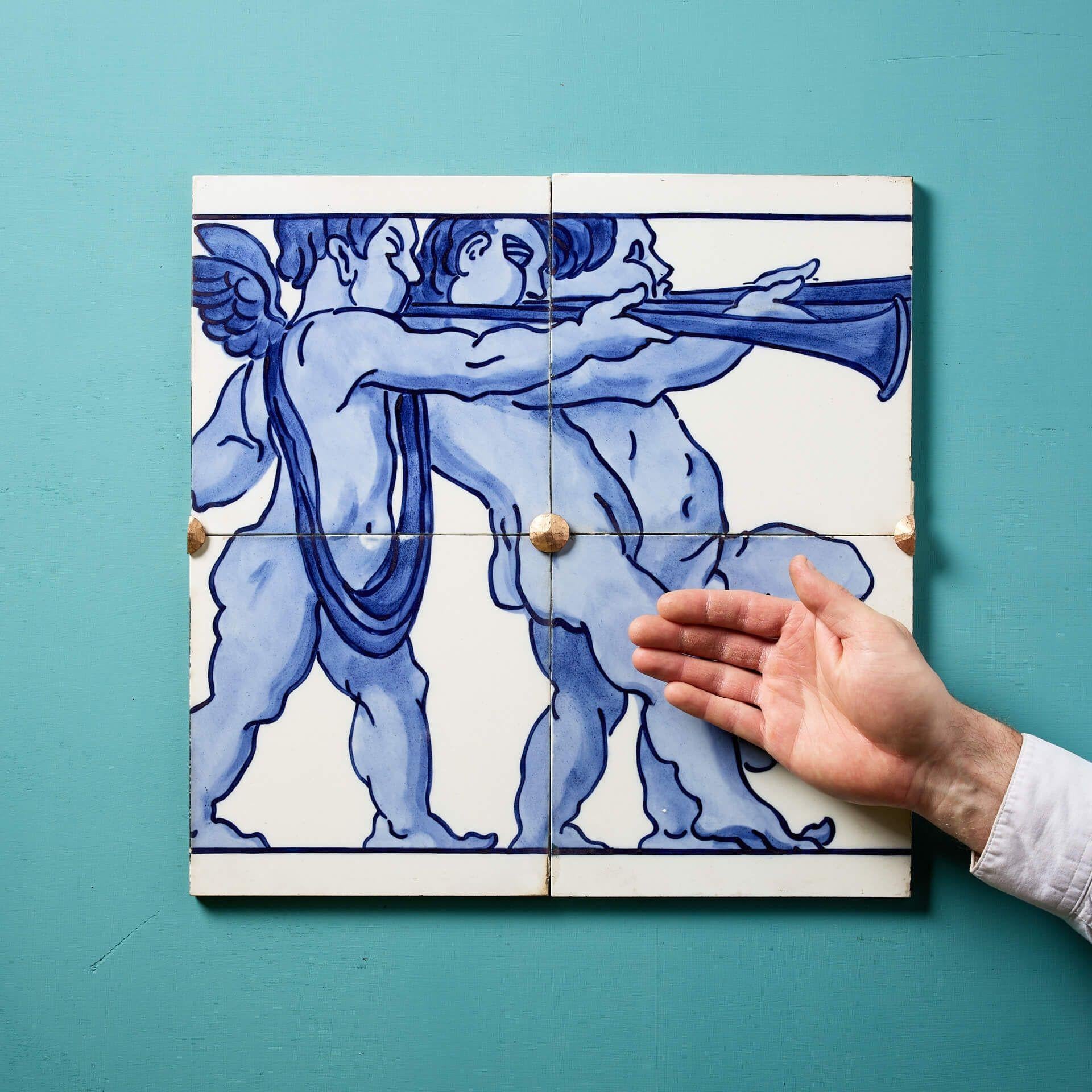 Un set di 4 antiche piastrelle in ceramica pressata a polvere di Minton Hollins (timbrate) che creano un pannello decorativo con fregio smaltato in bianco e blu raffigurante tre putti alati in stile rinascimentale che suonano corni o trombe.

Un