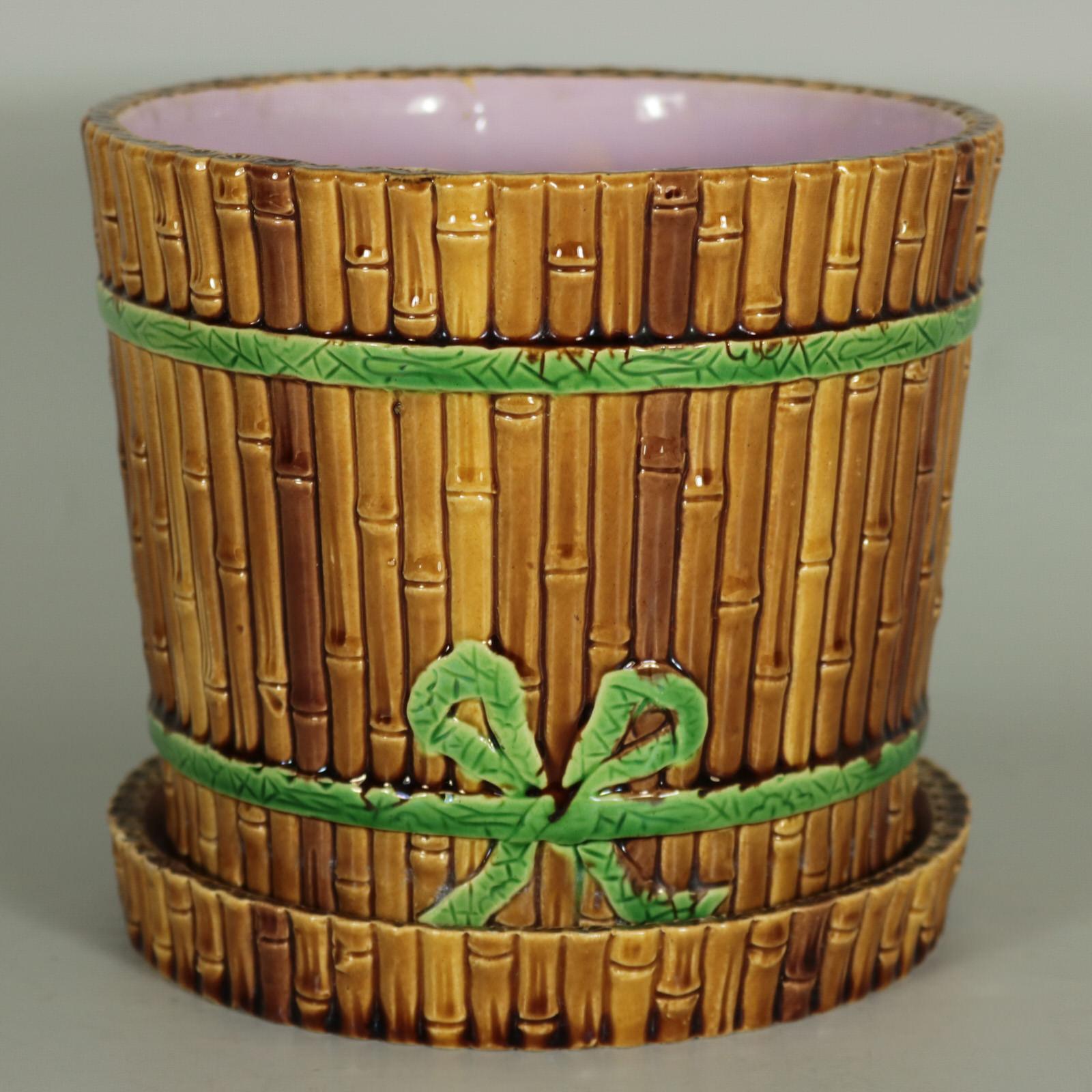 Minton Majolica planter and stand which features bamboo cane-effect sides, bound together with green ribbon. Brown ground version. Coloration: brown, green, pink, are predominant. The piece bears maker's marks for the Minton pottery. Marks include a
