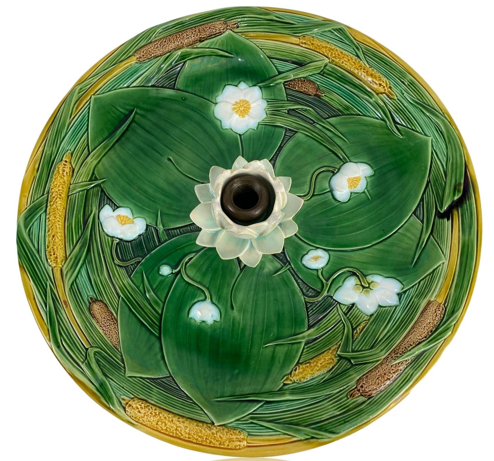 Centro de mesa de mayólica Minton, modelado naturalista como un estanque con agua simulada esmaltada en azul cian, con nenúfares esmaltados en verde y lirios de estanque en flor (loto), y juncos esmaltados en varios tonos de verde, con espadañas