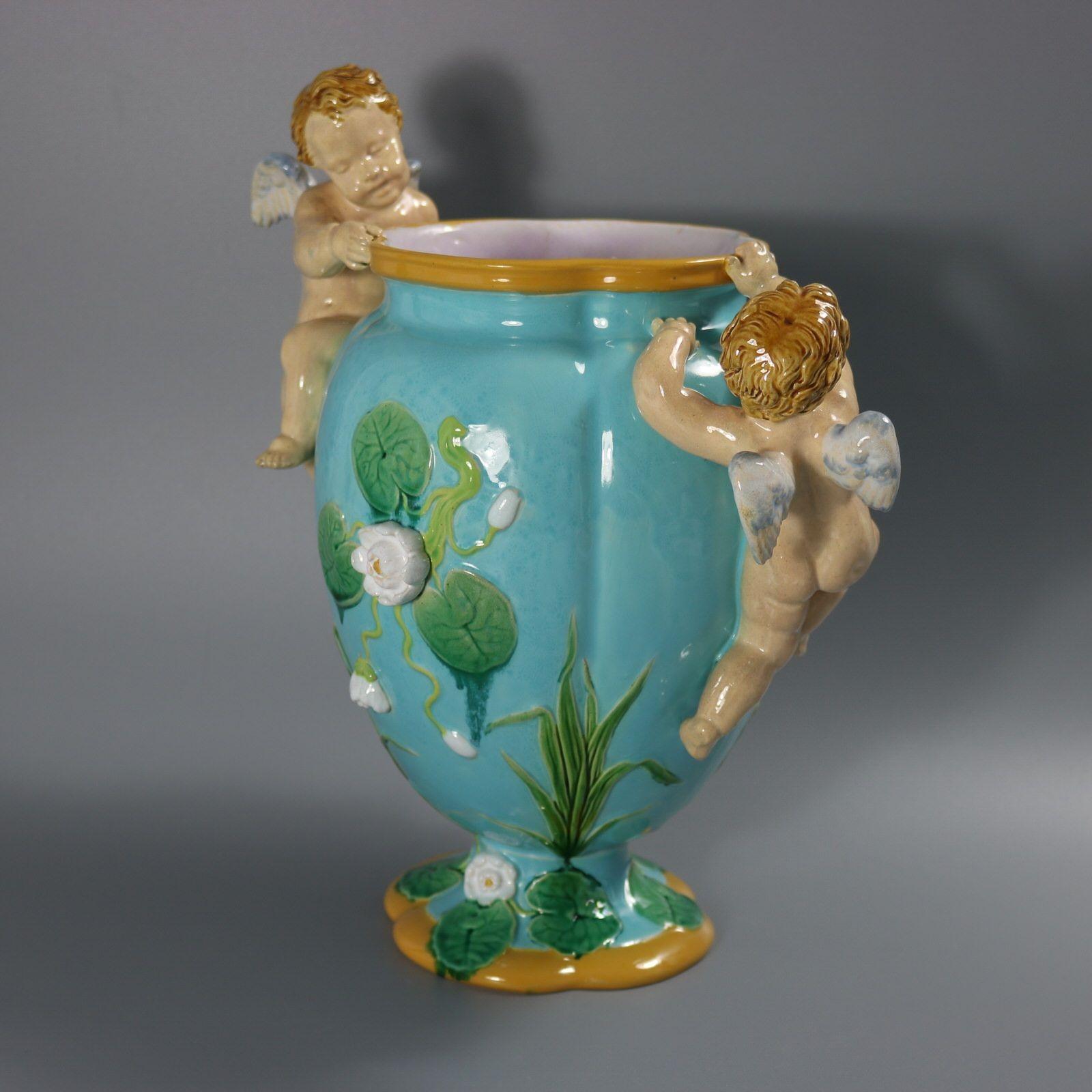 Vaso in maiolica di Minton con cherubini rampicanti e ninfee. Versione con fondo turchese. Colorazione: predominano il turchese, il verde e l'ocra. Il pezzo reca i marchi di fabbrica della ceramica Minton. Porta un numero di modello, 