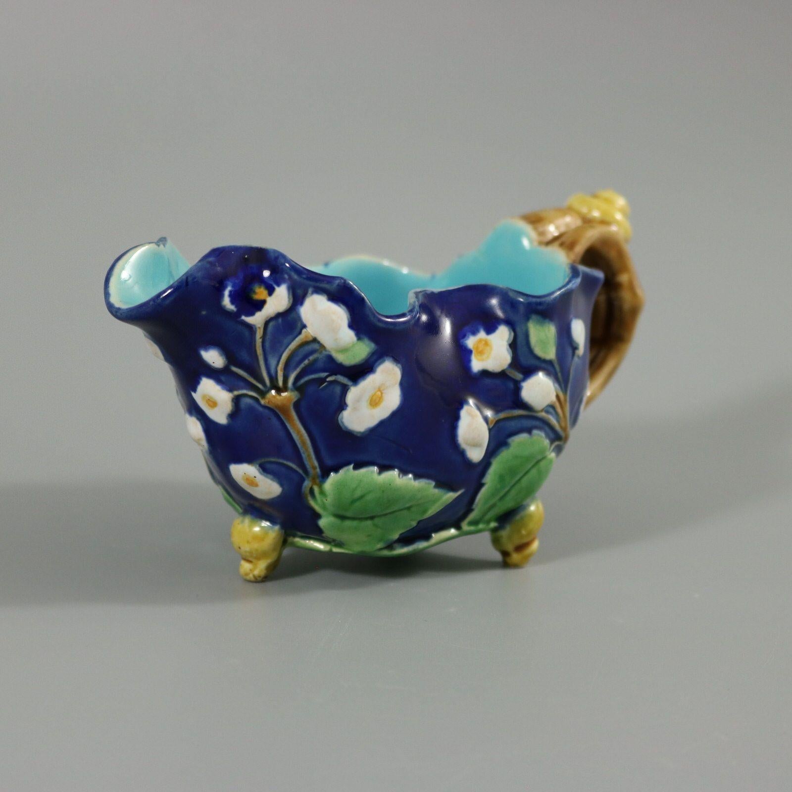 Minton Majolica creamer which features a blossoming branch, snail shell on handle and feet. Cobalt blue ground version. Colouration: cobalt blue, green, white, are predominant. The piece bears maker's marks for the Minton pottery. Bears a pattern