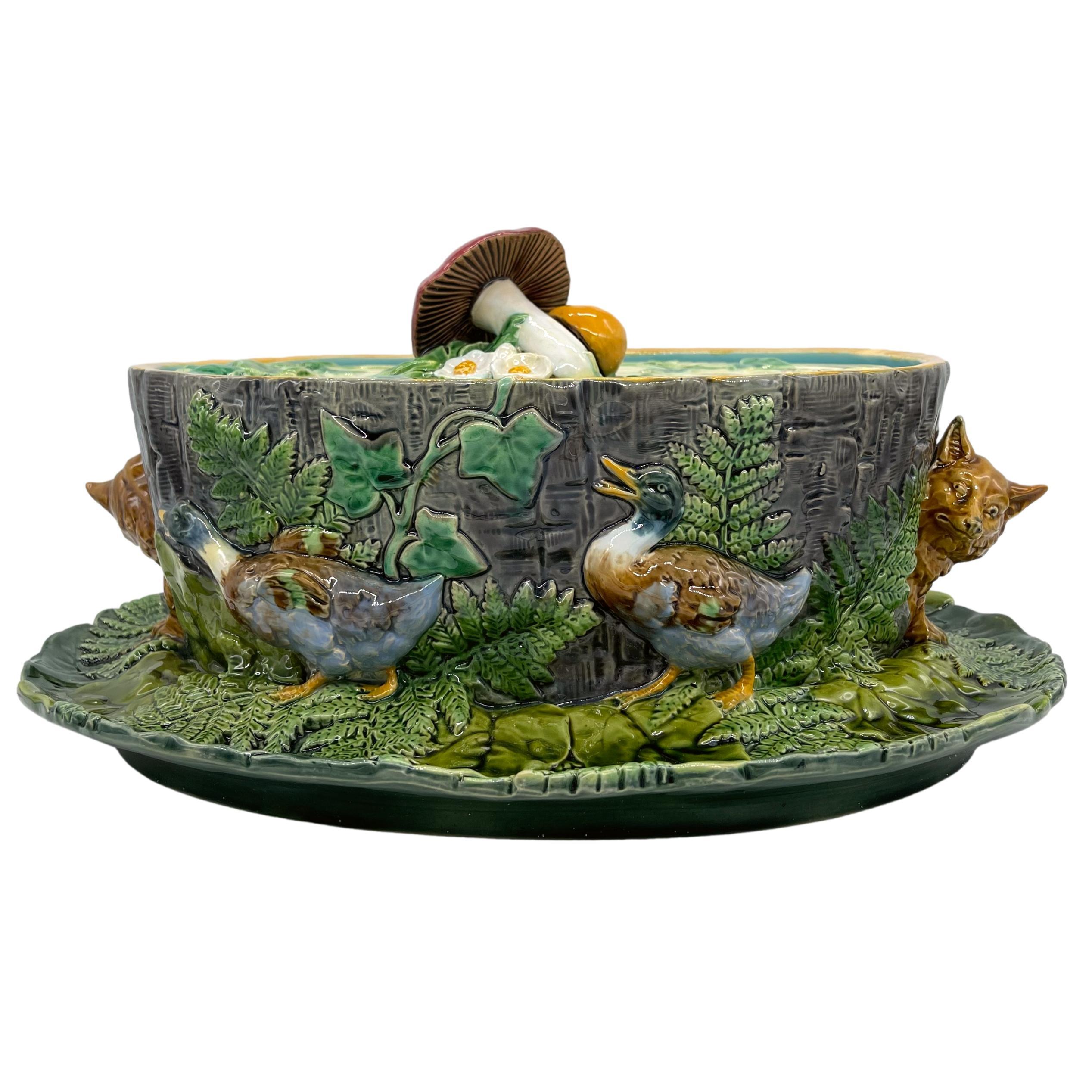 Minton Majolica Game Tureen, the oval tureen naturalistically molded as a tree trunk encircled by brightly glazed Mallard ducks, with two peering and highly interested foxes flanking either side, the interior glazed in turquoise, the integral stand