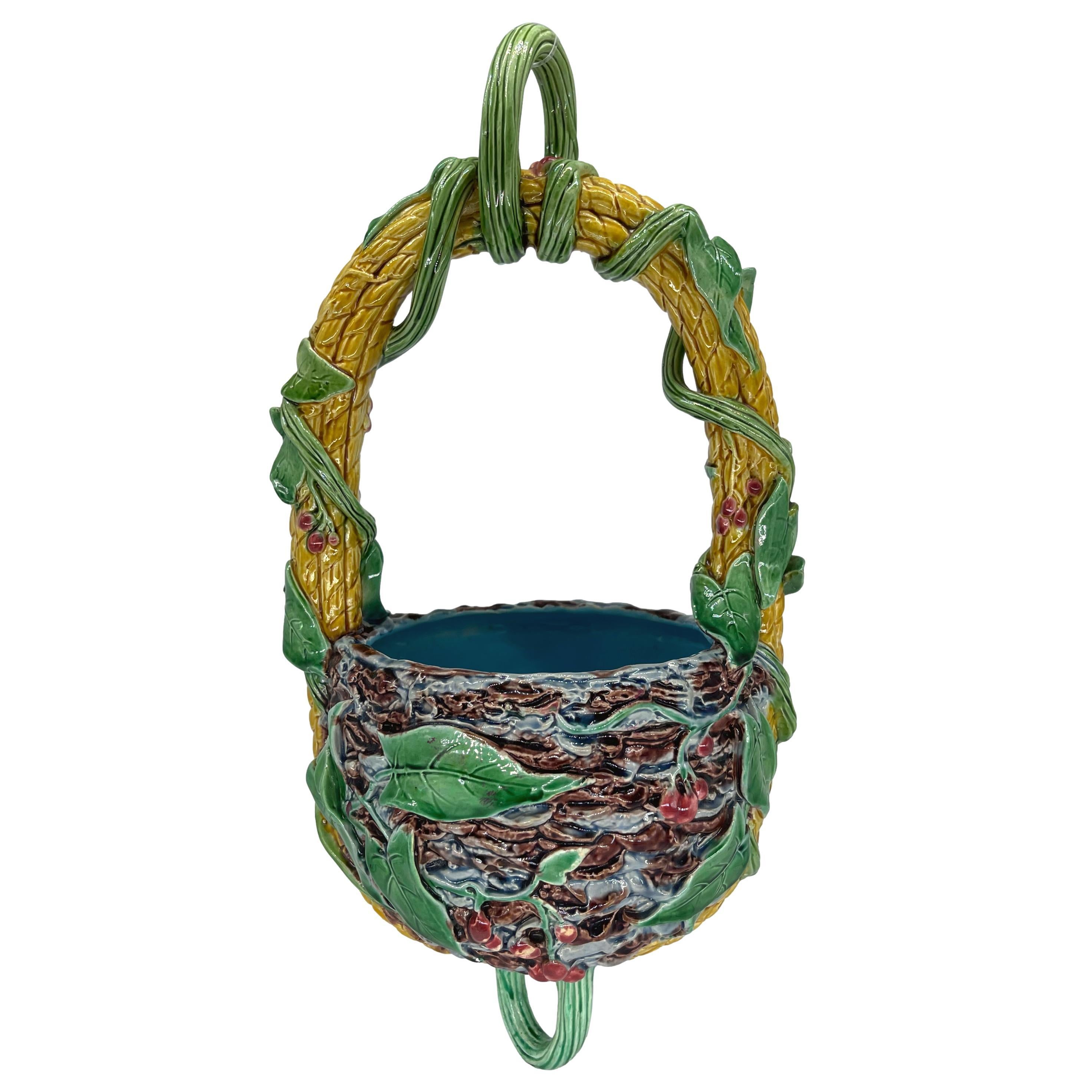 Minton Majolica Hanging Planter/Basket, the planter molded as a birds nest with red glazed cherries and green leaves, the interior glazed in turquoise, the woven bail handle glazed in yellow, with leaves, tendrils, and vines, surmounted by a looped