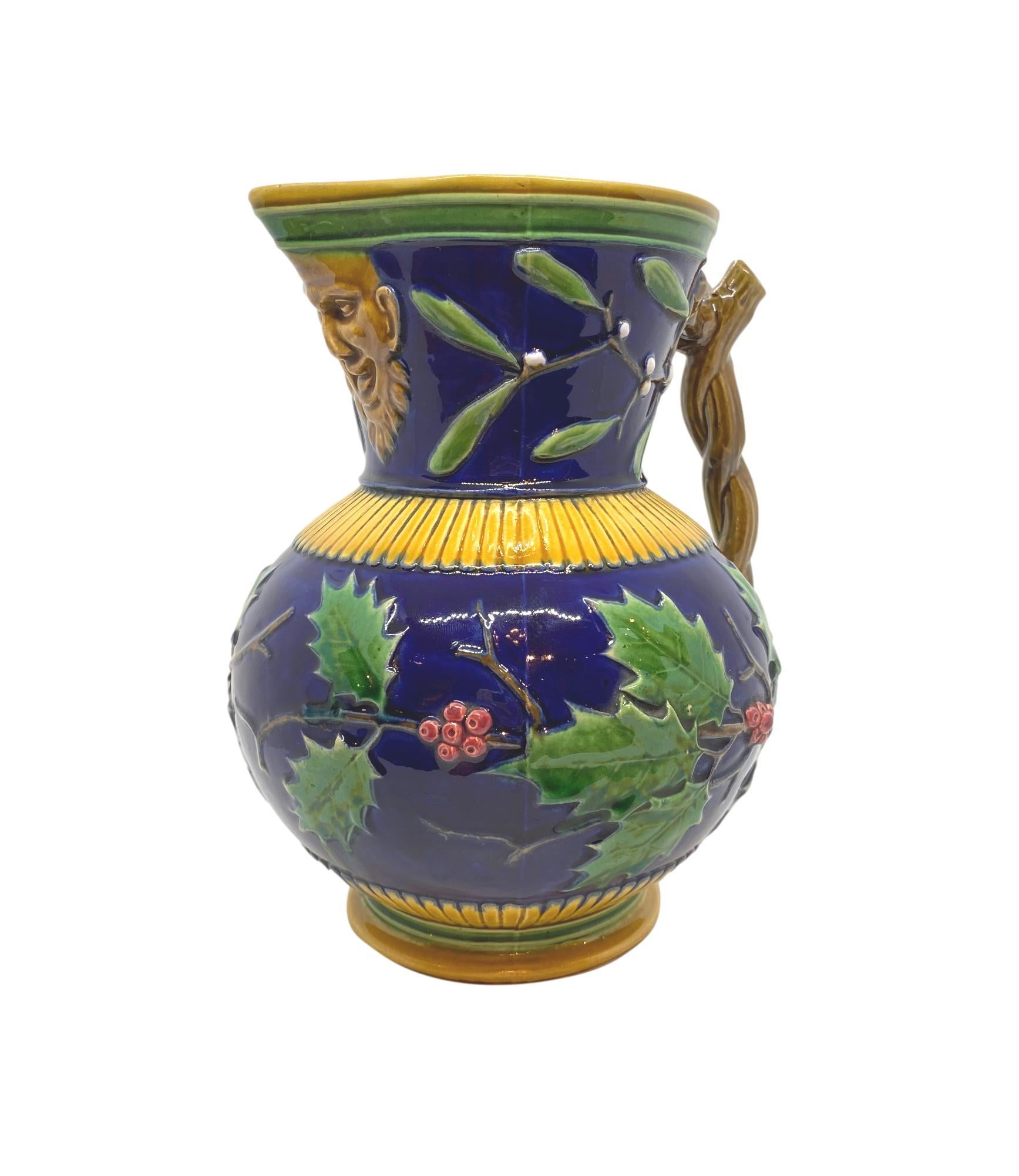 Minton Majolica large Christmas wine ewer, the body of the jug with relief molded holly branches encircling, with mistletoe, on a cobalt blue ground, the spout with a Bacchus mask, the handle formed as entwined twigs, impressed marks to reverse: