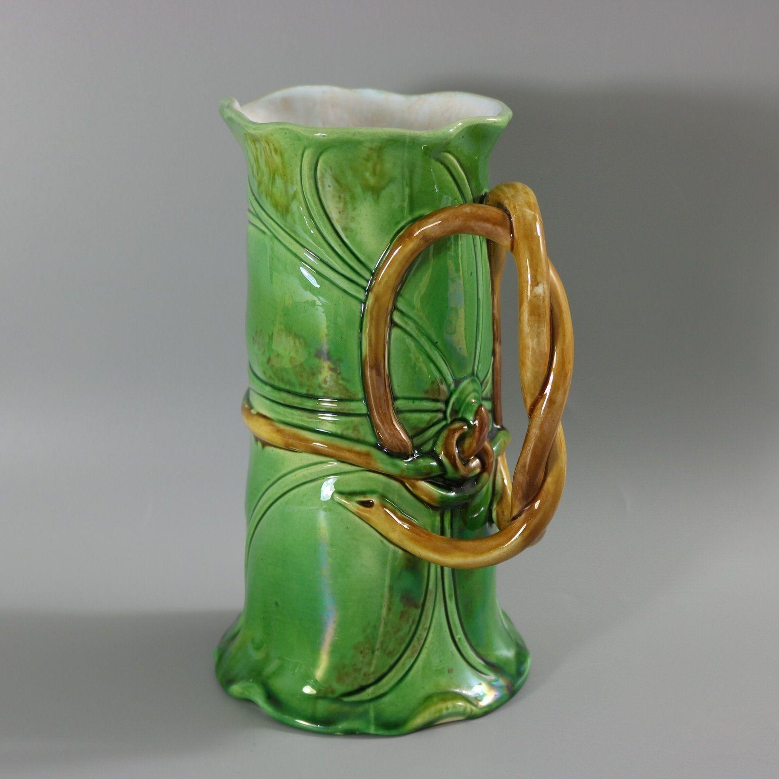 Minton Majolica jug/pitcher which features overlapping leaves and a stem-like handle. Colouration: green, brown, white, are predominant. The piece bears maker's marks for the Minton pottery. English diamond registration mark for the date 23/??/1859.