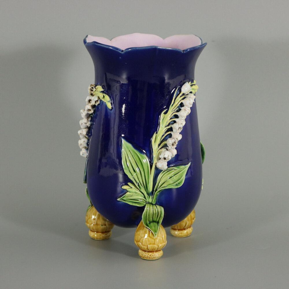 Minton Majolica vase which features Lily of the Valley flowers, sprouting from bulb feet. Cobalt blue ground version. Colouration: cobalt blue, green, white, are predominant. The piece bears maker's marks for the Minton pottery. Bears a pattern