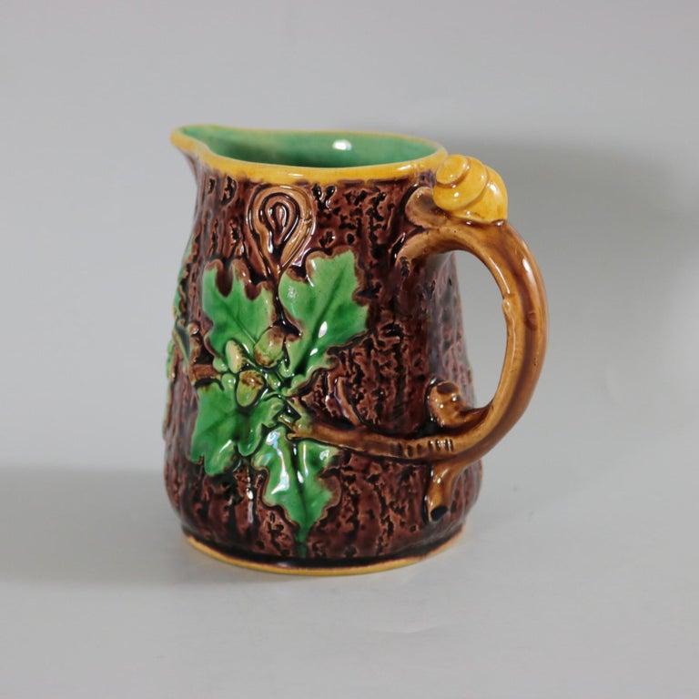 Minton Majolica jug/pitcher which features oak leaves and acorns to the sides and a snail to the handle. Colouration: brown, green, yellow, are predominant. The piece bears maker's marks for the Minton pottery. Marks include a factory specific date