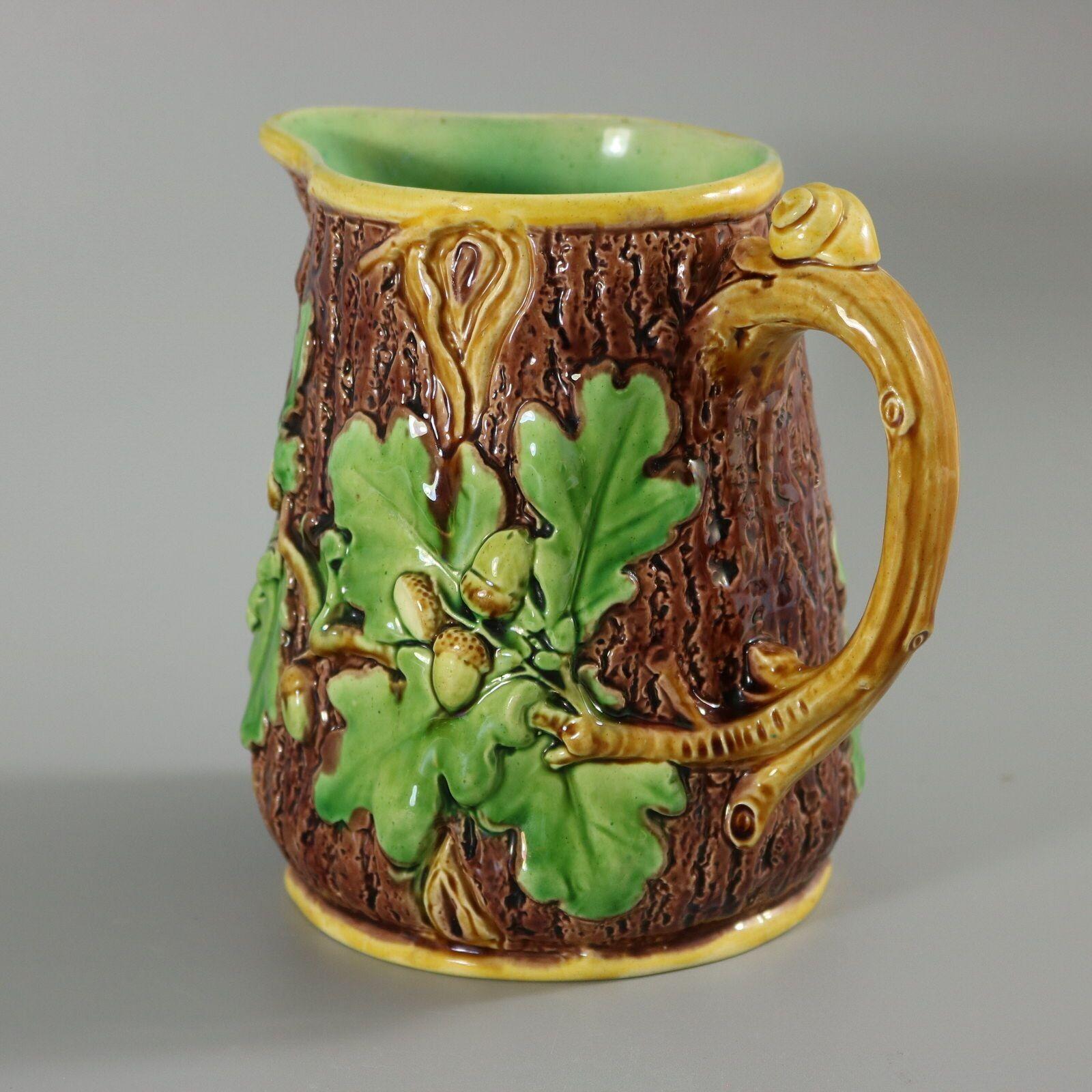 Minton Majolica jug / pitcher which features oak leaves and acorns to the sides and a snail to the handle. Colouration: brown, green, yellow, are predominant. The piece bears maker's marks for the Minton pottery. Bears a pattern number, '12'. Marks