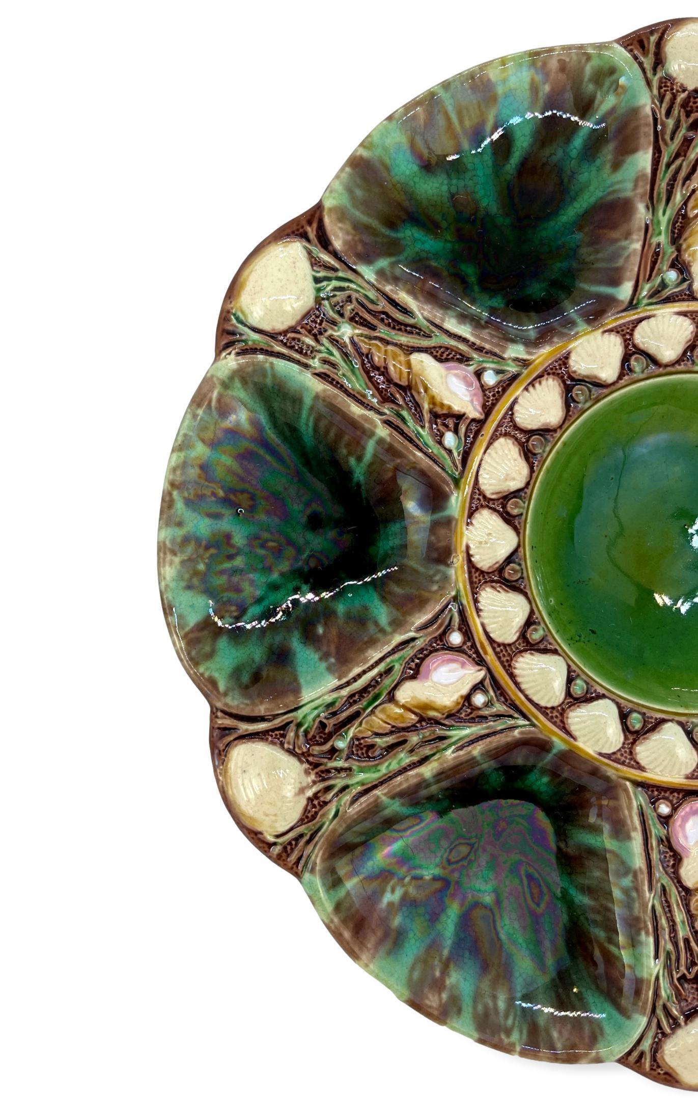 Minton Majolica six-well oyster plate, glazed in mottled greens and browns, the reverse impressed, 'Minton,' and date cypher for 1871, molded British Registry Lozenge for 20 March 1867 (when the design was registered), and impressed design number