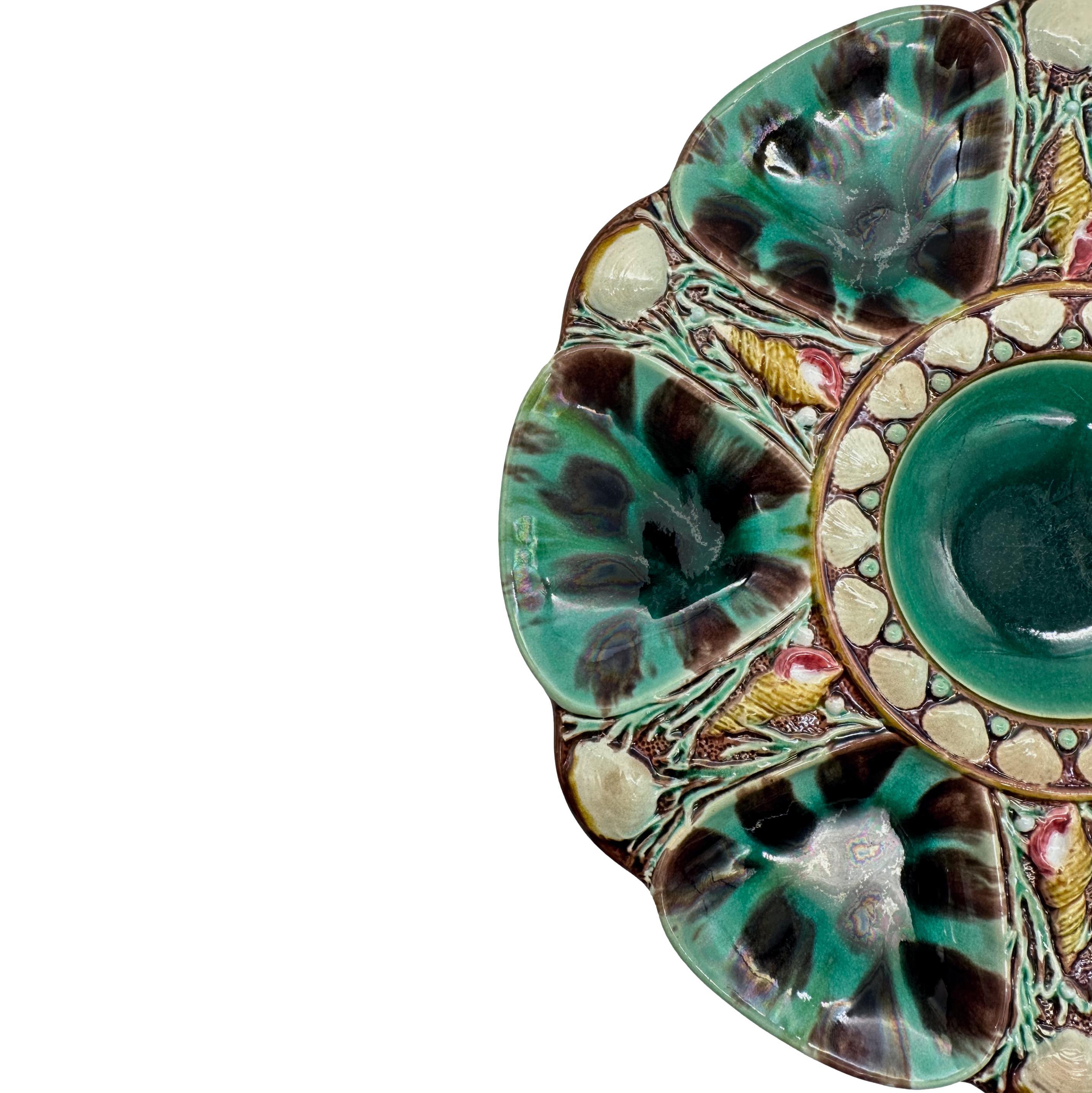 Minton Majolica Oyster Plate, the relief-molded dish with six wells glazed in mottled leopard spots of green and dark brown, each well separated by shells and seaweed, the center well glazed in green and banded with shells, the reverse with