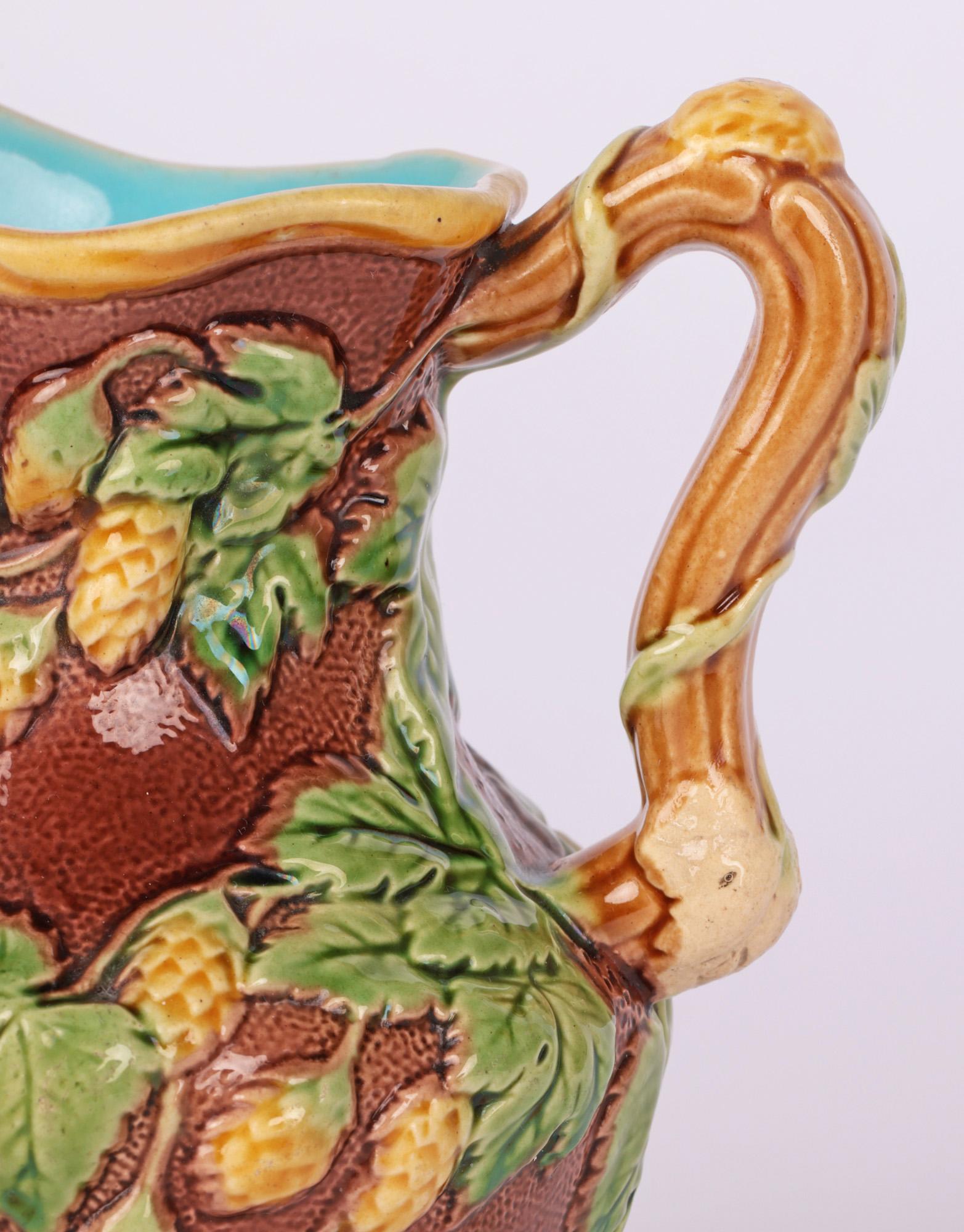 A fine early and unusual Minton majolica art pottery ale jug decorated with relief fruiting designs dating from 1866. The finely made pottery jug is of round bulbous shape with a pinched neck and shaped pouring and with a traditional twig formed