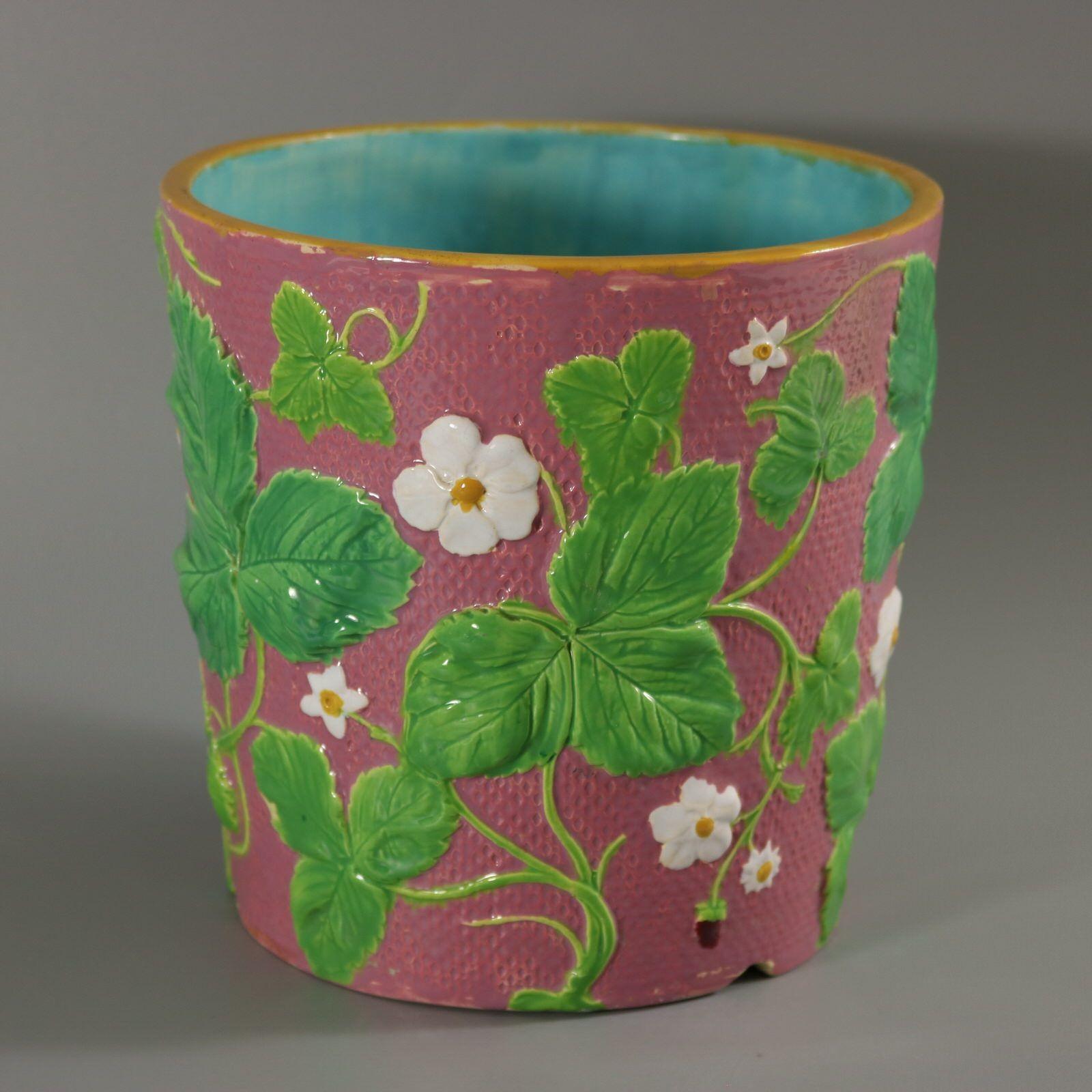 Minton Majolica planter which features strawberries, leaves and blossoms. Pink ground version. Colouration: pink, green, white, are predominant. The piece bears maker's marks for the Minton pottery. Bears a pattern number, '811'. Marks include a