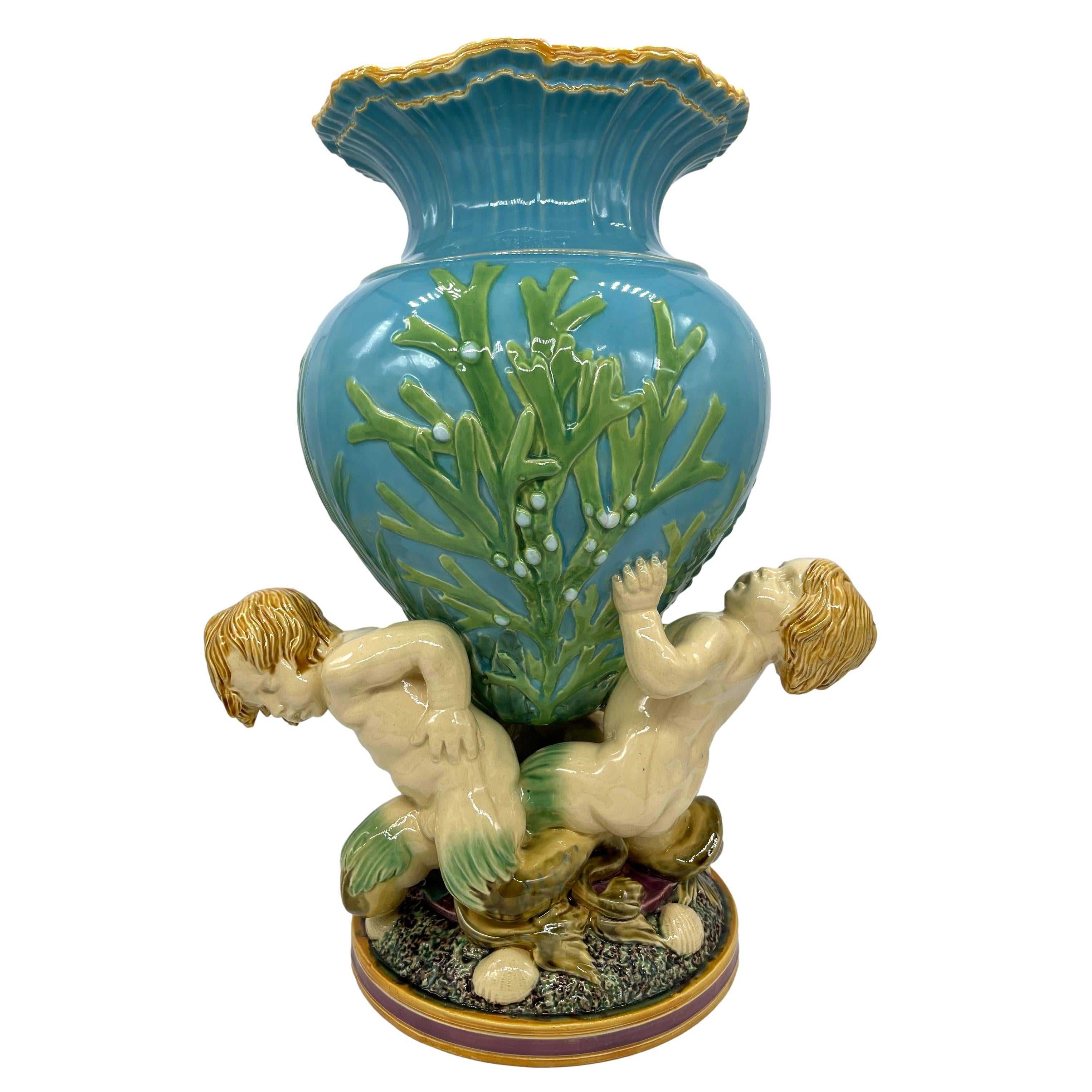 Large Minton Majolica 'Marine Flower Vase,' modeled as Triton's Golden Palace at the bottom of the sea, the amphora-shaped vase with green glazed seaweed on a turquoise ground, supported by three young Tritons, on an 8-in pedestal base with