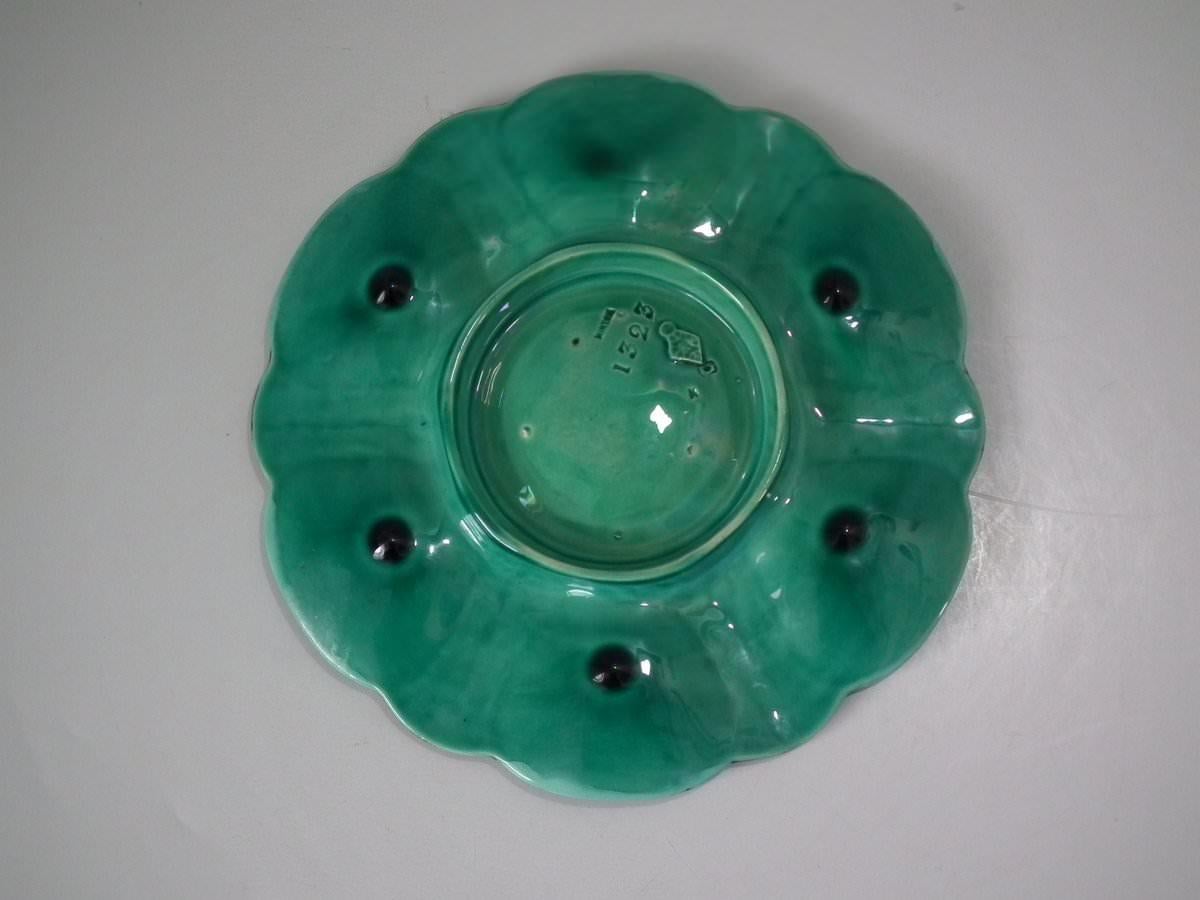 Minton Majolica oyster plate which features six shell shaped wells with seashell surrounds. Turquoise ground version. Coloration: turquoise, green, cream, are predominant. The piece bears maker's marks for the Minton pottery. Bears a pattern number,