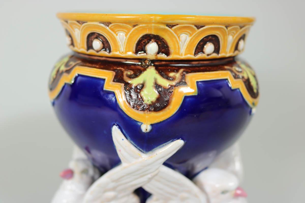 Minton Majolica vase which features three doves, supporting a vessel on their wings. Cobalt blue ground version. Coloration: cobalt blue, white, ochre, are predominant. The piece bears maker's marks for the Minton pottery. Bears a pattern number,