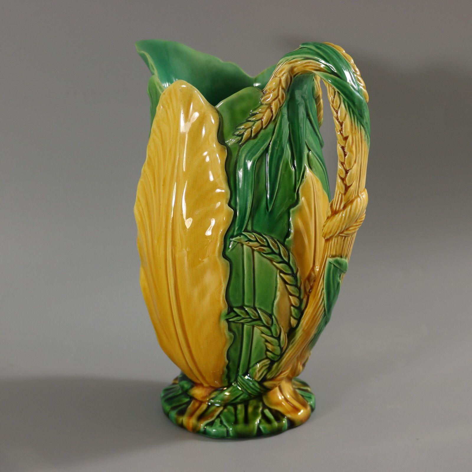 Minton Majolica jug/pitcher which features corn forming the handle. The sides in the form of banana leaves. Colouration: green, yellow, are predominant. Marks include a factory specific date cipher for the year 1856.