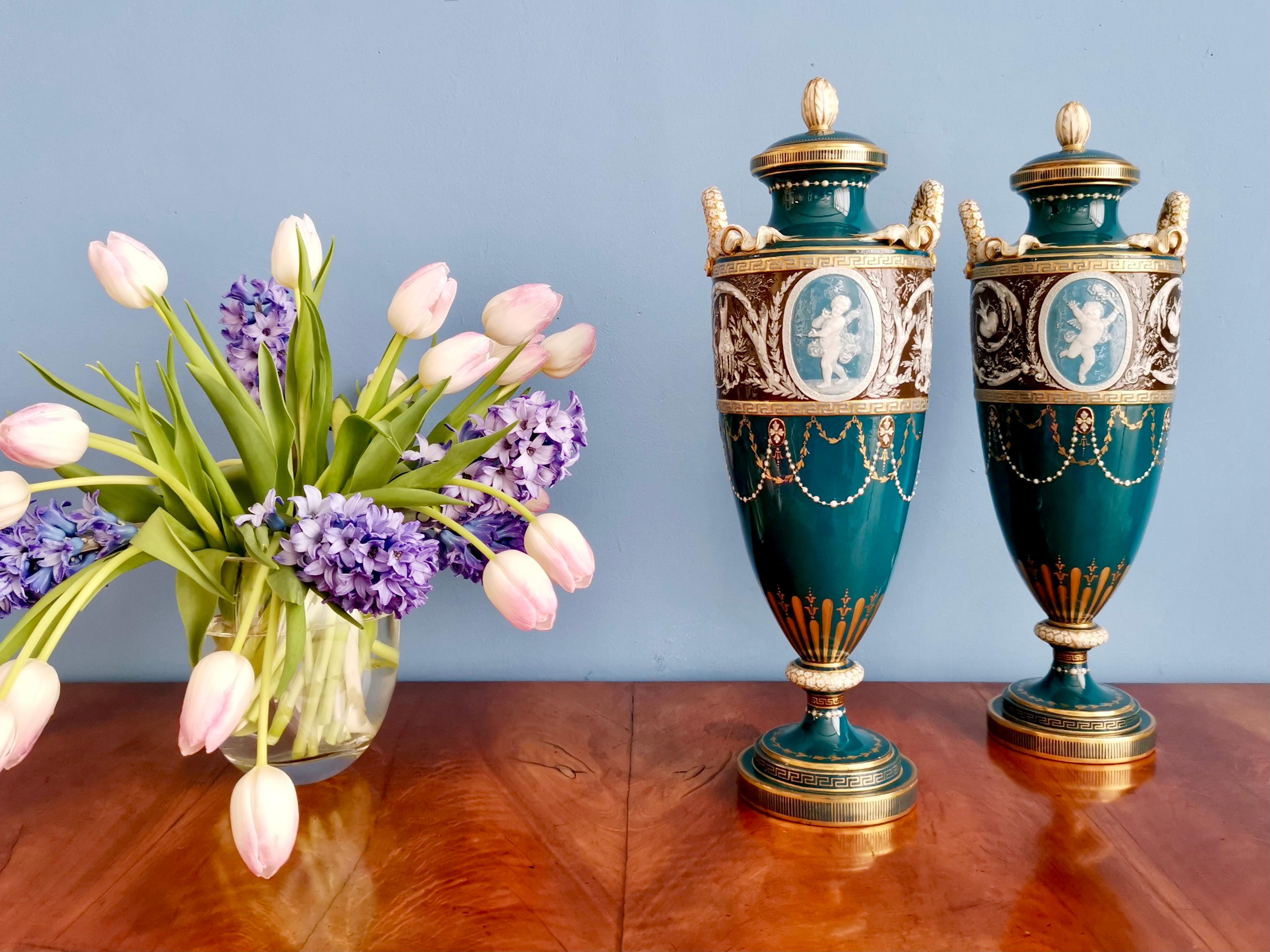 On offer is a sublime and rare pair of vases or urns with covers, made by Minton between 1873 and 1891, which was the Victorian era. The vases have a tall and slender shape and sublime pâte-sur-pâte decorations by Harry Hollins, who worked with the