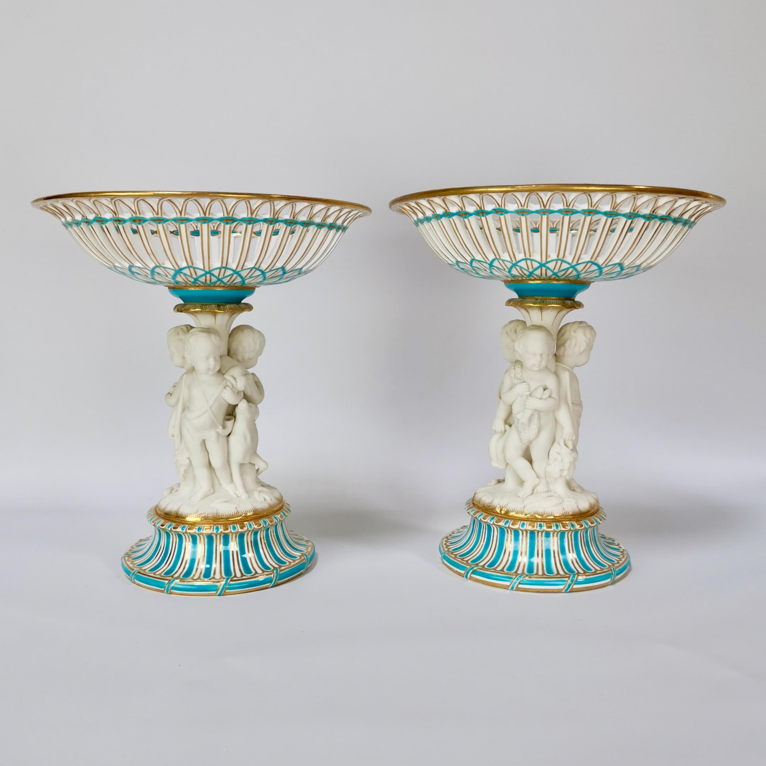 This is a spectacular pair of tazzas or comports made by Minton in about 1880, which was the Victorian era. The stems of the tazzas hold three white Parian porcelain hunting cherubs and their dog. These tazzas would make a fabulous display on your