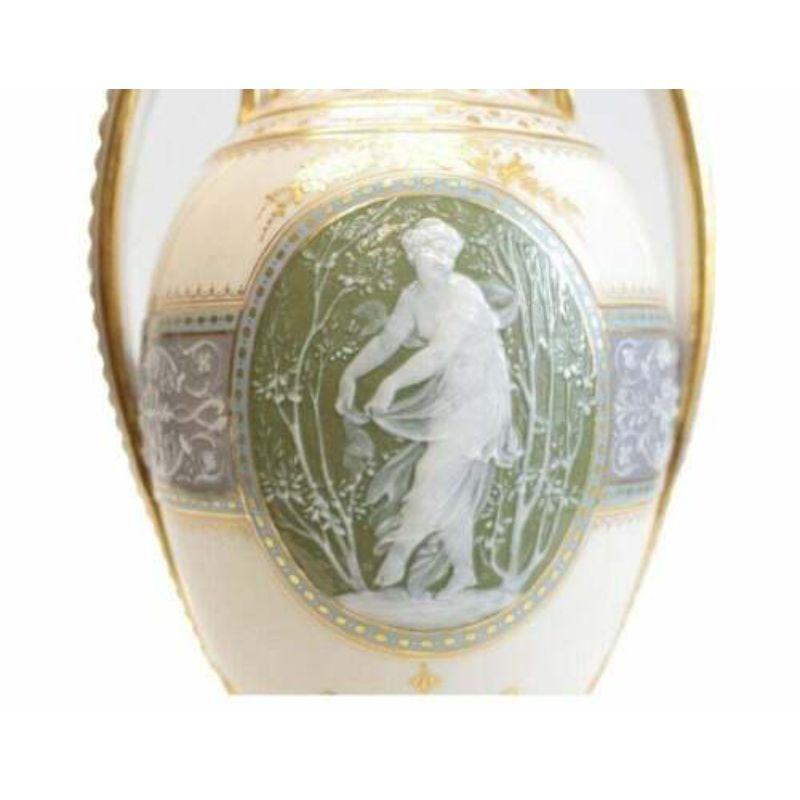 Minton pate-sur-pate decorated porcelain lidded urn by L Birks, Dated 1892.

A Minton Pate Sur Pate teal and light grey porcelain vase and cover on an ivory color ground of twin handled baluster form, the central oval medallion depicting a young